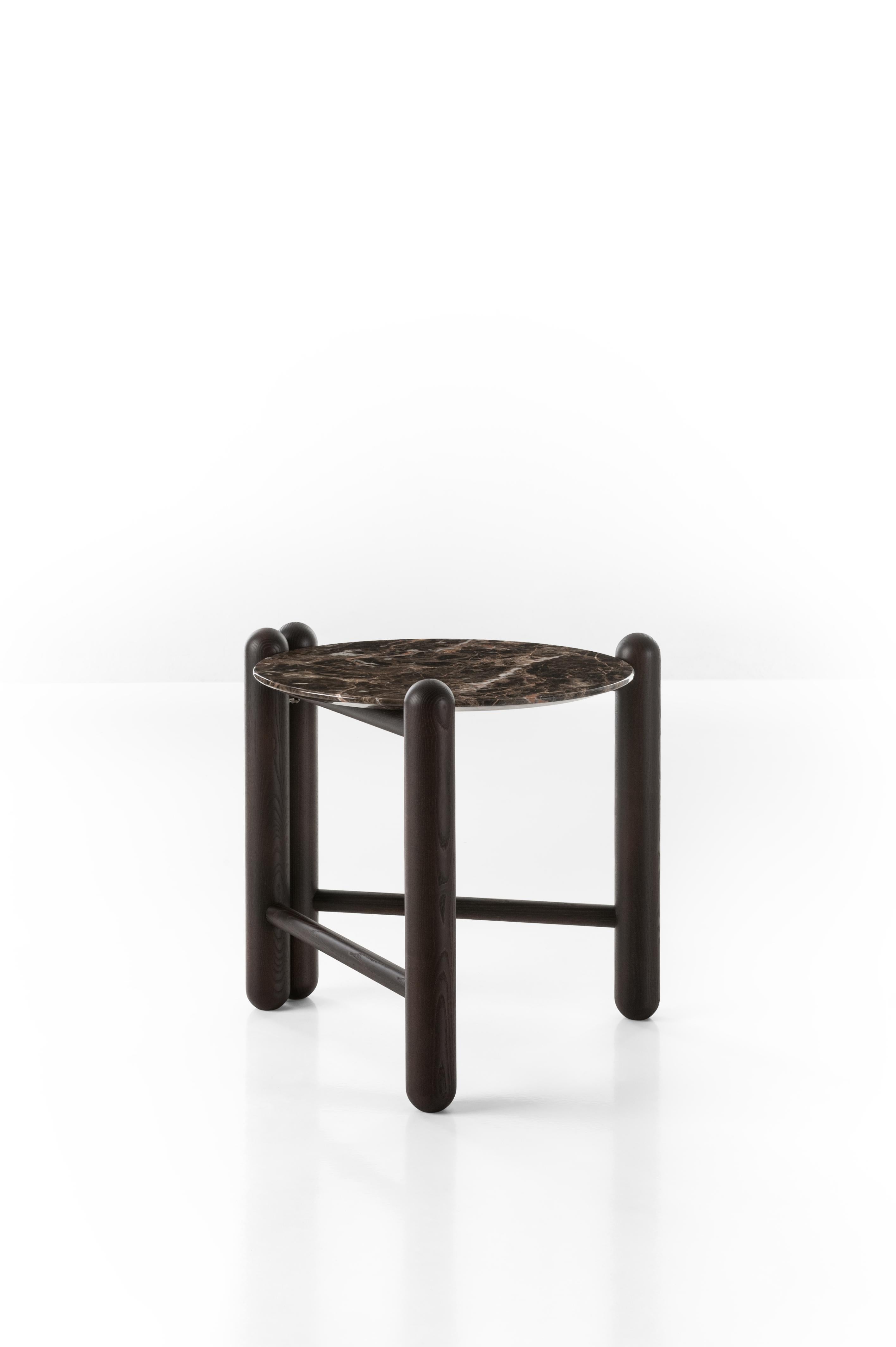 This table completes and enriches the company’s first line of upholstered pieces with sumptuous elegance. The folding structure in ash wood post has a round top available in such precious materials as “Emperador Brown” marble or glass “Stopsol” ,
