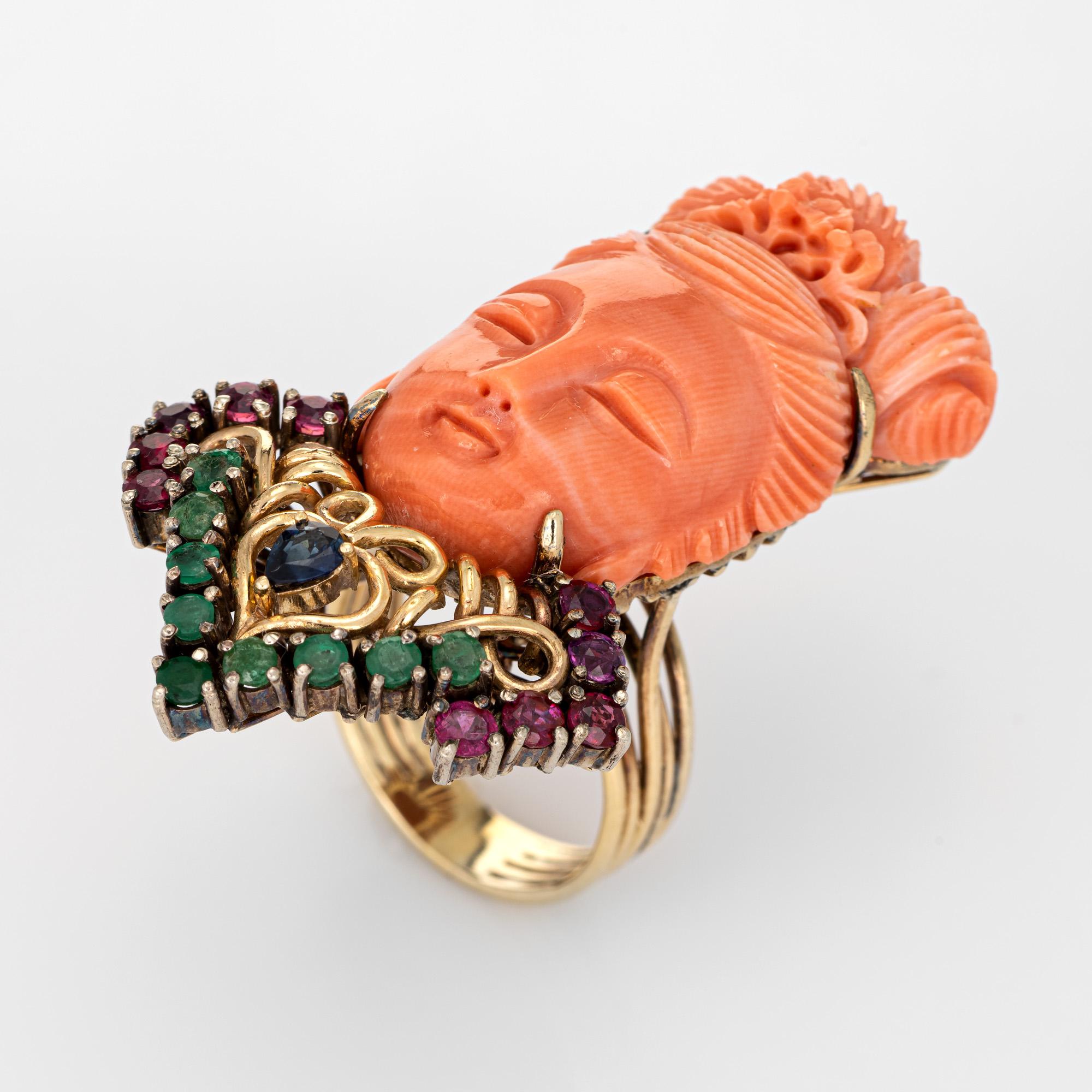 Elaborate and finely detailed cocktail ring depicting Guanyin (circa 1960s) crafted in 14 karat yellow gold. 

Coral is carved in the form of Guanyin measuring 35mm x 20mm. Ten rubies are estimated at 0.05 carats each (0.50 carats total estimated