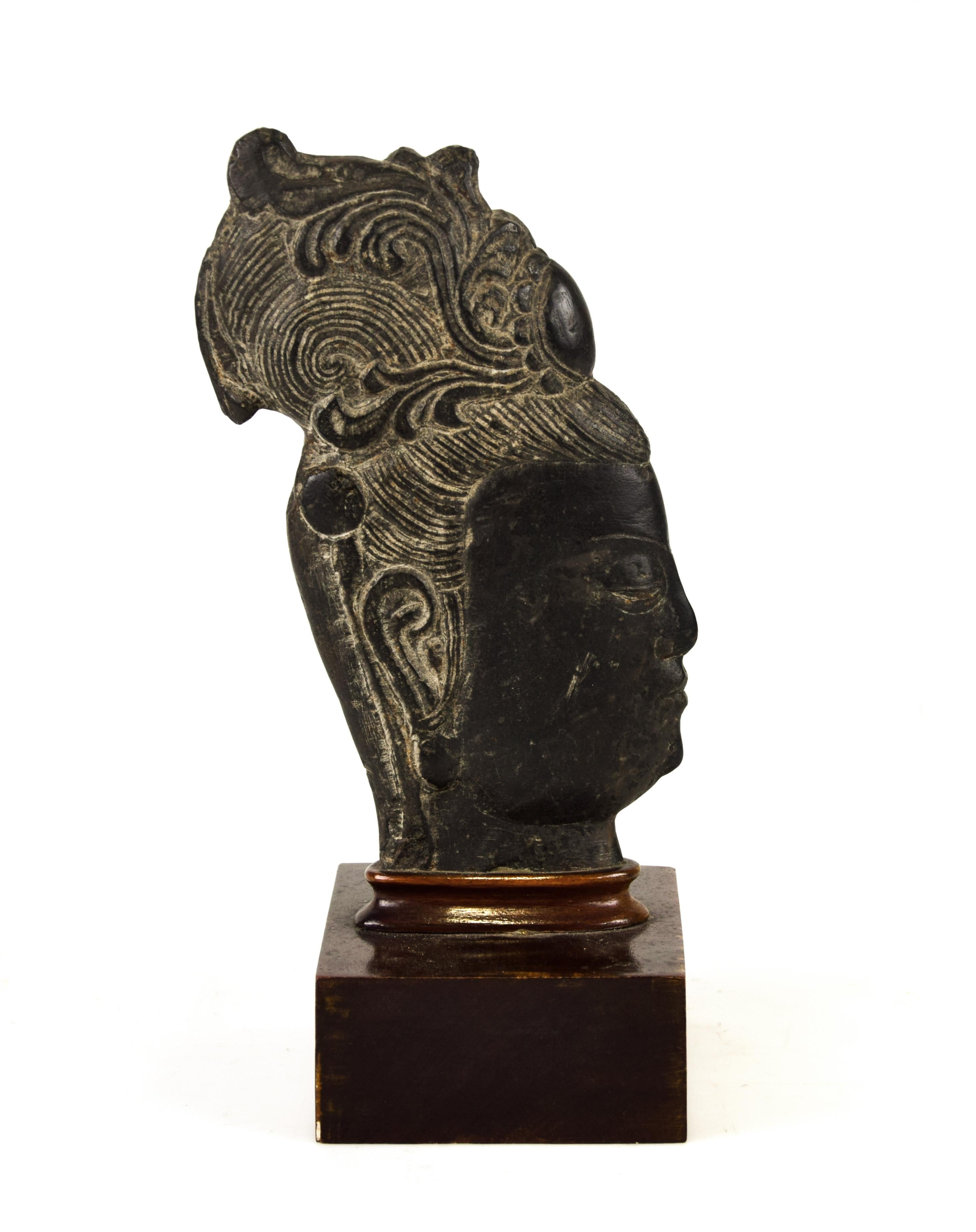 Guanyin's Head is a charming gray-black stone sculpture by an anonymous Chinese master of the 20th century.

Depicting the profile of the divinity's head with the hairstyle in low and high relief, this oriental sculpture has the base in glued