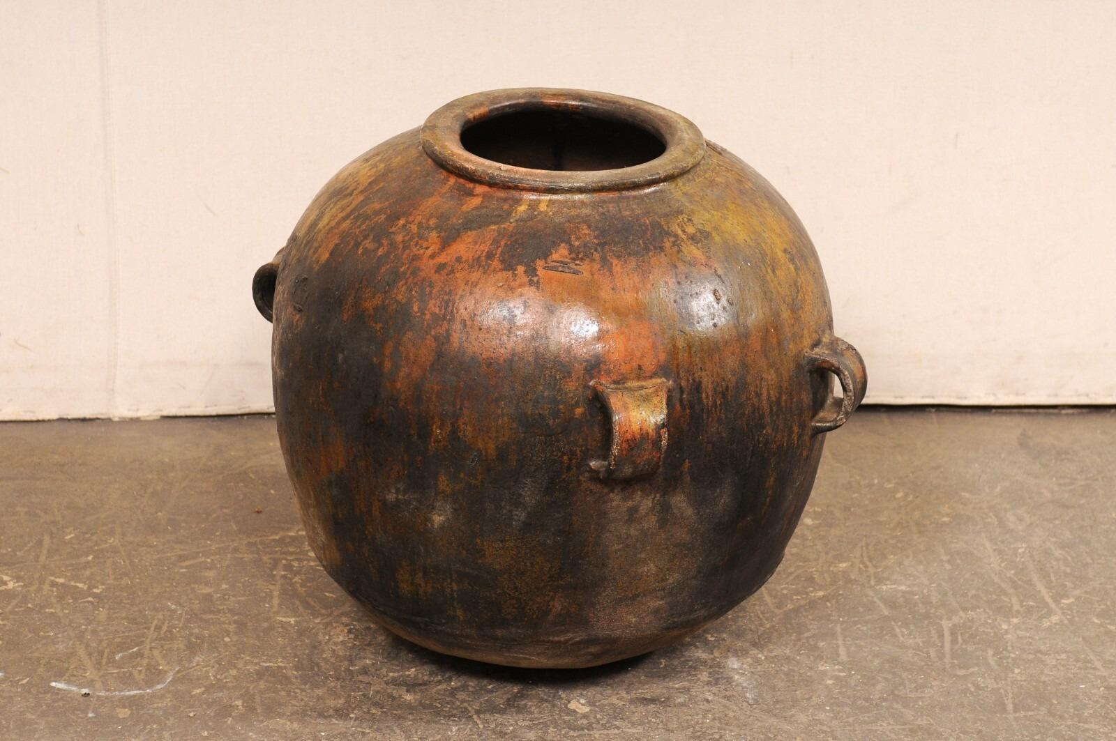 A larger-sized Guatemalan clay pot with beautiful glazed finish. This vintage cooking vessel has been made of clay, has a rounded-shape with flattened bottom and recessed top hole with rounded lip. The pot has four handles about its perimeter. This