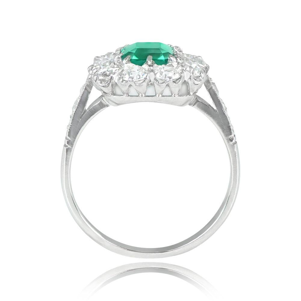 This stunning ring features a 0.97-carat emerald-cut, no-oil Colombian emerald at its center, set in prongs. The emerald is encircled by a halo of H-I color, VS2-SI1 clarity old European cut diamonds, with additional diamonds along the shoulders,