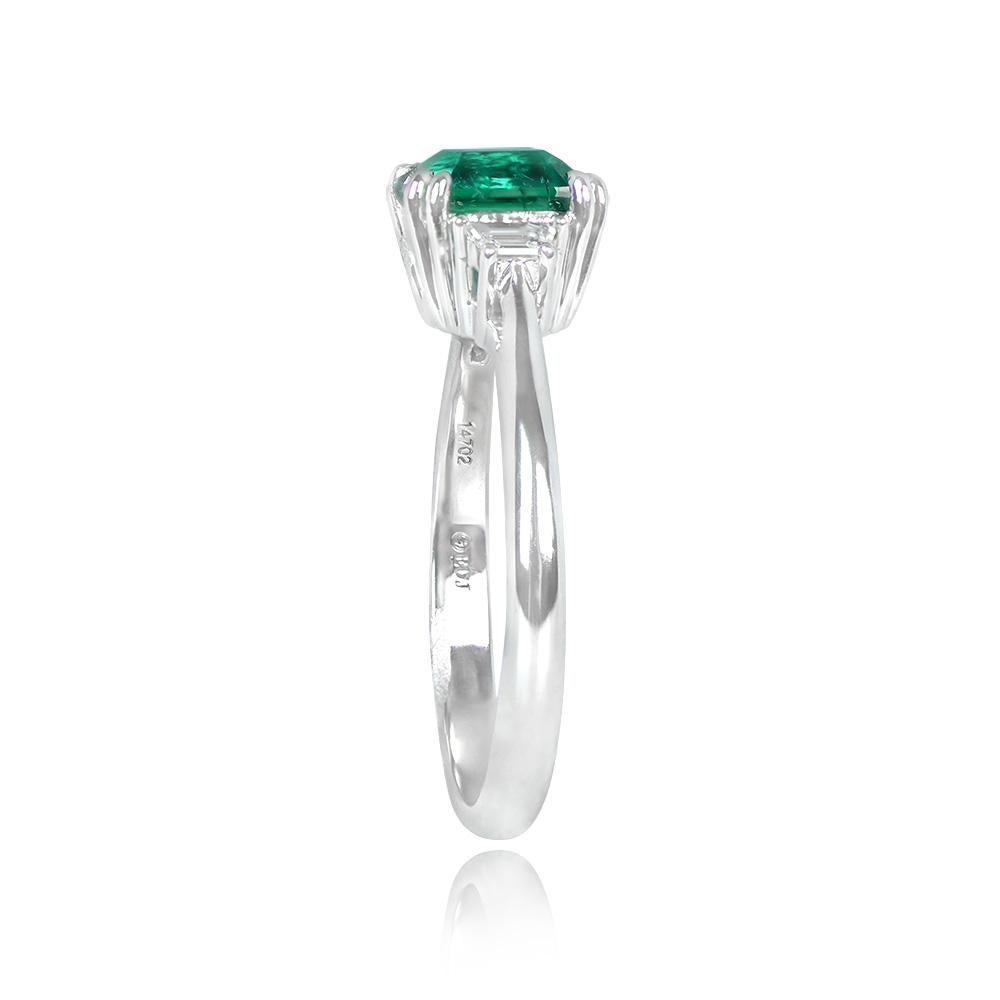A stunning platinum ring with a 1.58-carat natural Colombian no-oil emerald, emerald-cut, and prong-set. Trapezoid-cut diamonds on each side of the center stone weigh a total of 0.16 carats, with G color and VS2 clarity. The emerald's authenticity