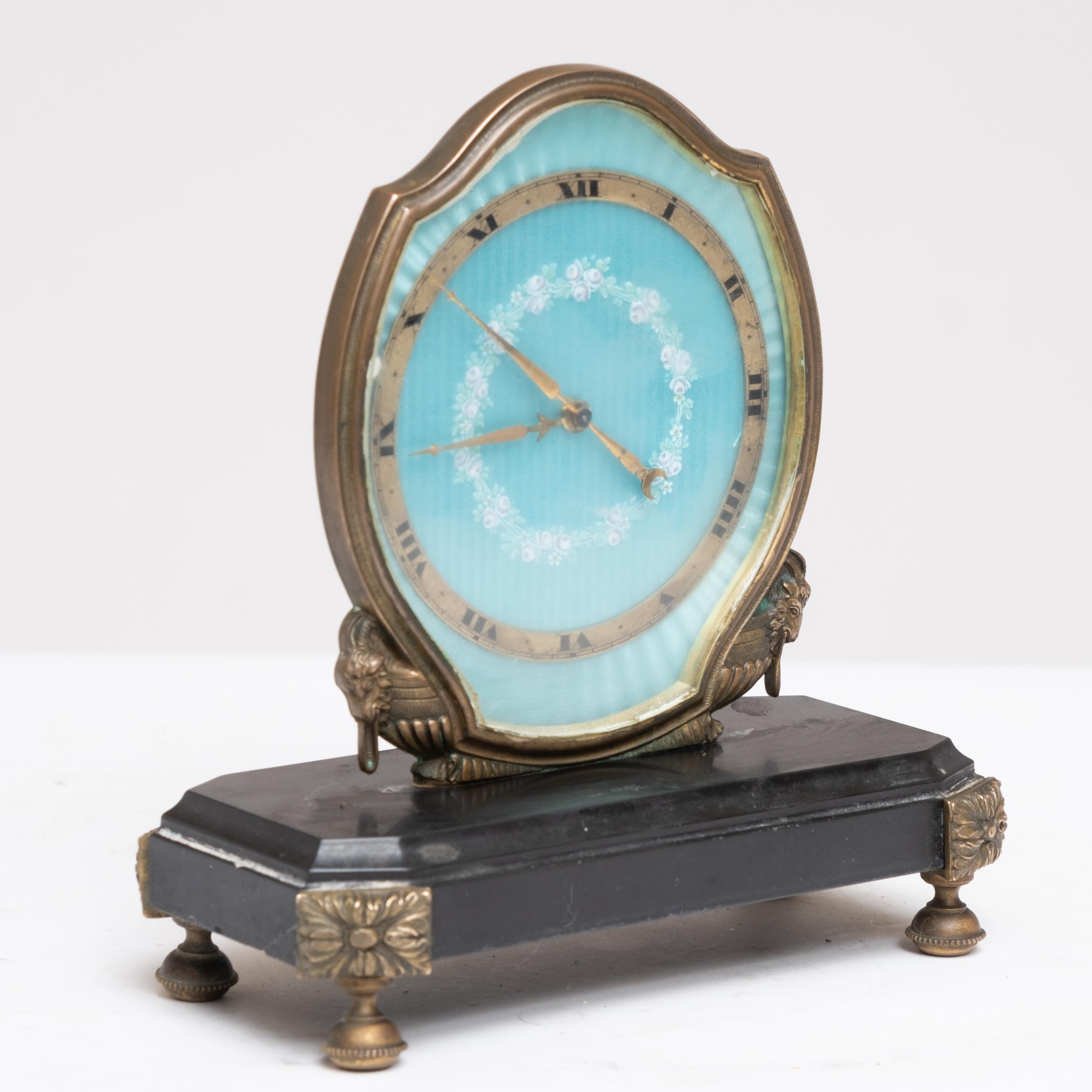 Art Deco Gubelin eight-day desk clock with sonnerie chimes, originating from Switzerland in the early 20th century. This timepiece features a light blue guilloche face, beautifully enameled with pink and green flower depictions. The clock has ormolu