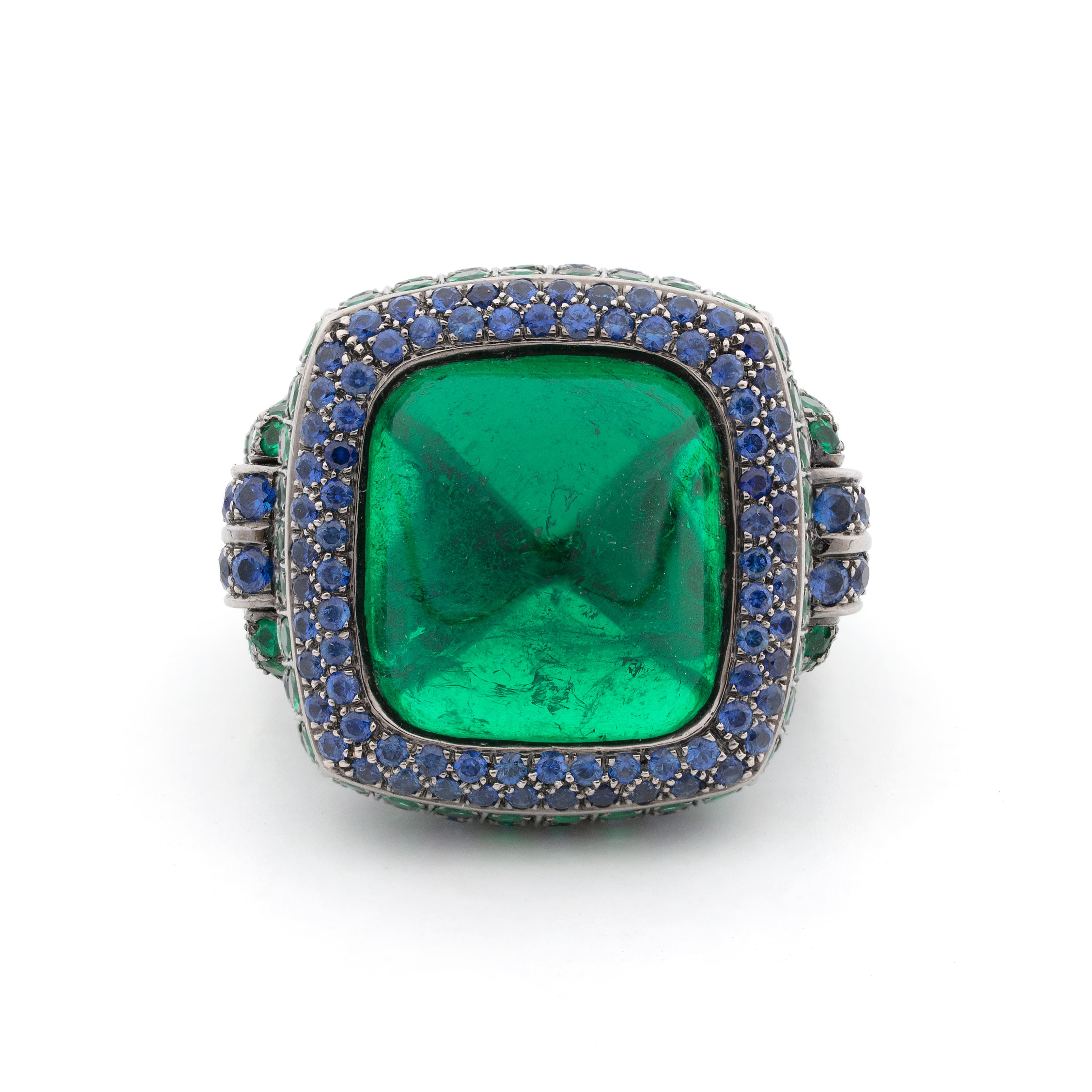 This is a spectacular Colombian emerald and blue sapphire ring from Boucheron. The centerpiece of this magical ring is the 15-carat sugarloaf Colombian emerald, which comes with a Gubelin certification. The stunningly clear emerald is surrounded by
