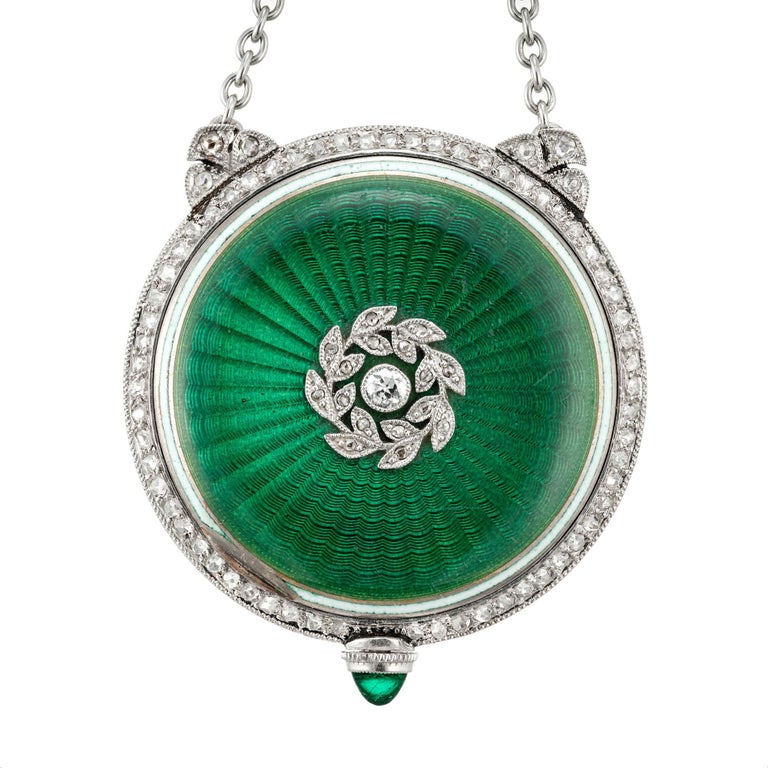 Early 1900’s Platinum and 18k white gold pendant watch necklace. Retailed by Gubelin circa 1915-1920. Manual wind movement. Green enamel accented with rose and old mine cut Diamonds with a cabochon emerald on the crown. the watch has a Patek