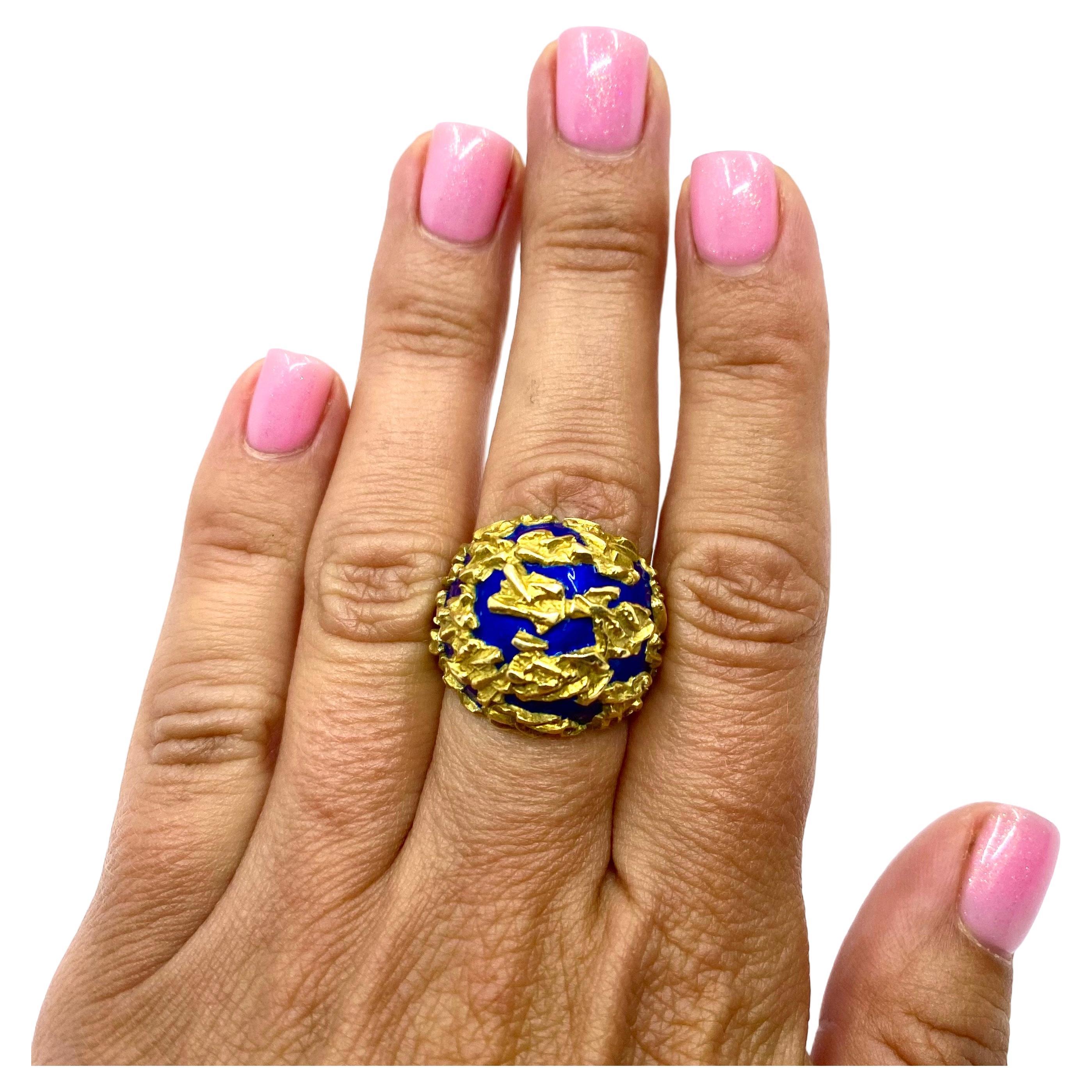An eloquent Gubelin dome ring, made of 18k gold and blue enamel.
The ring has abstract design with textured gold splashes set on the enamel background. Brightness of enamel creates an appealing contrast with the gold’s hue. The shank is textured as