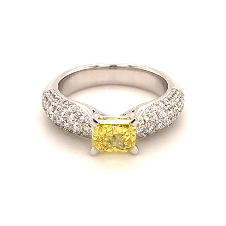 This elegant ring in white gold 750 is created by Gübelin, a famous Swiss jeweller. Its center of attraction is a 1.20 ct fancy vivid yellow radiant cut diamond with a vs1 clarity. The diamond is GIA certified. It is surrounded by 78 brilliant cut
