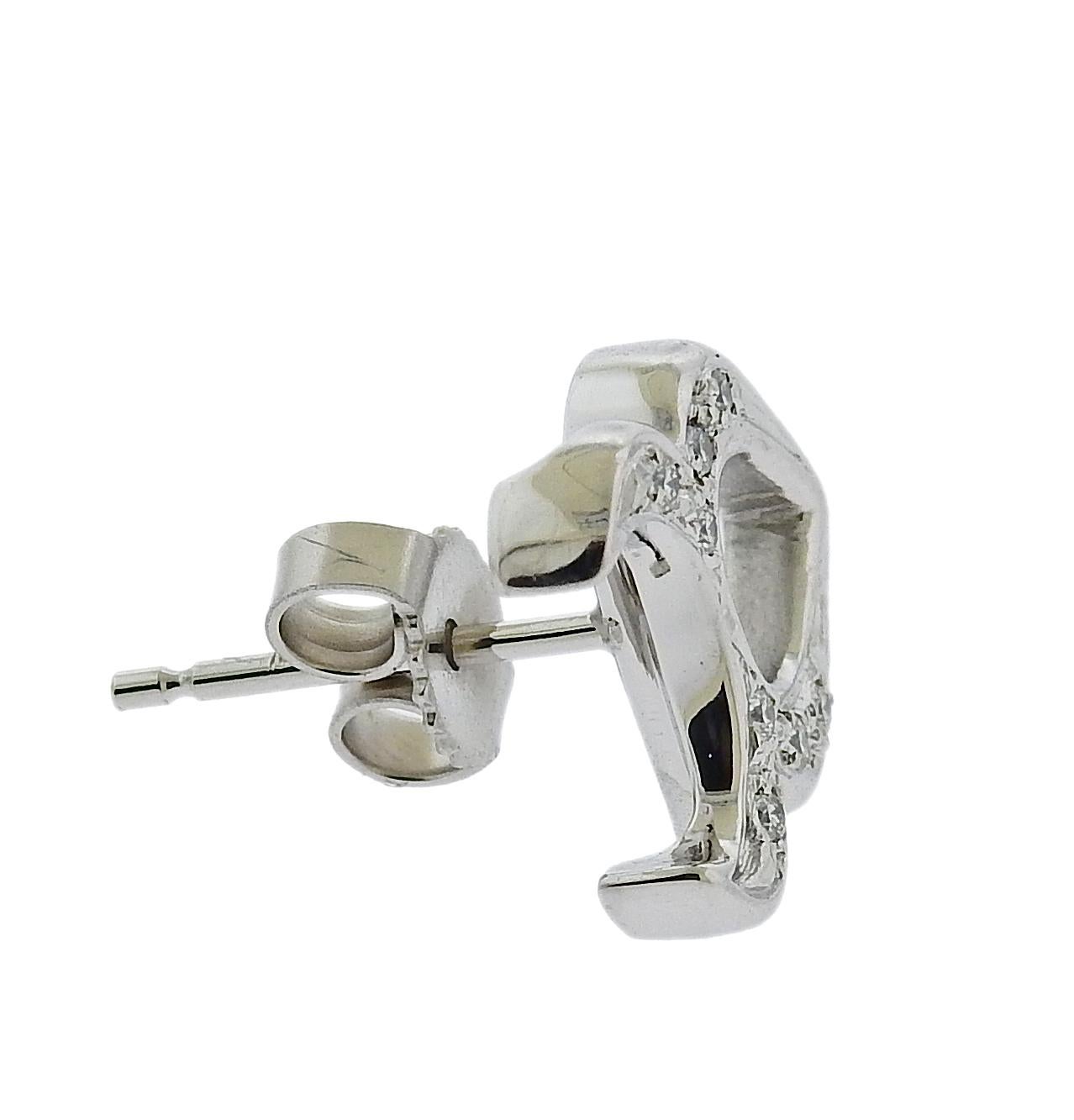 18k white gold stud earrings, with Taurus zodiac sign. By Gubelin. With approx. 0.10ctw in G/VS diamonds. Earrings are 13mm x 11mm. Weigh 4.6 grams. Marked: Gubelin mark, 750.