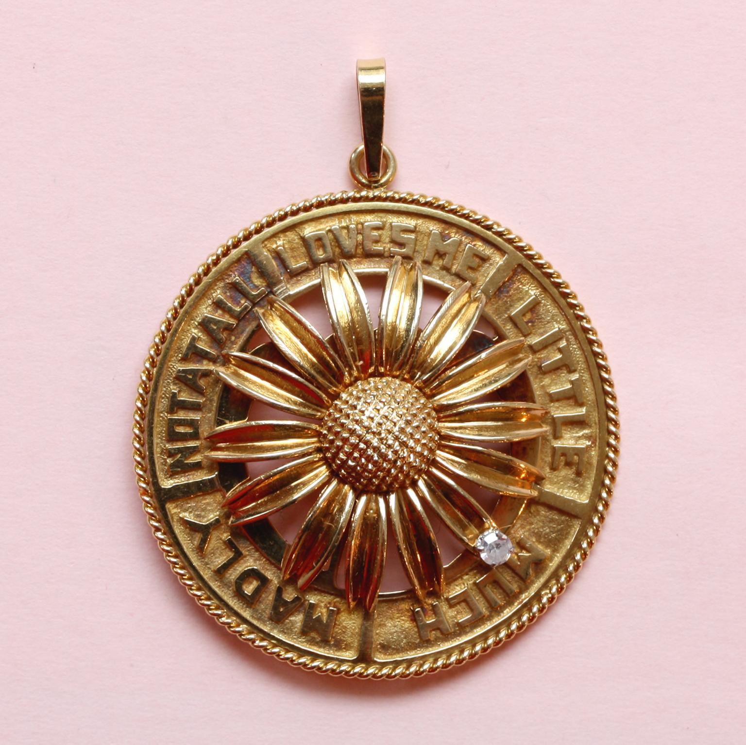 A large round 18 carat gold mechanichal charm with a spinning daisy in the center, one of the petals of the daisy has a brilliant cut diamond that spins around and tells you how much love there is: LOVES ME - LITTLE - MUCH - MADLY - NOT AT ALL,