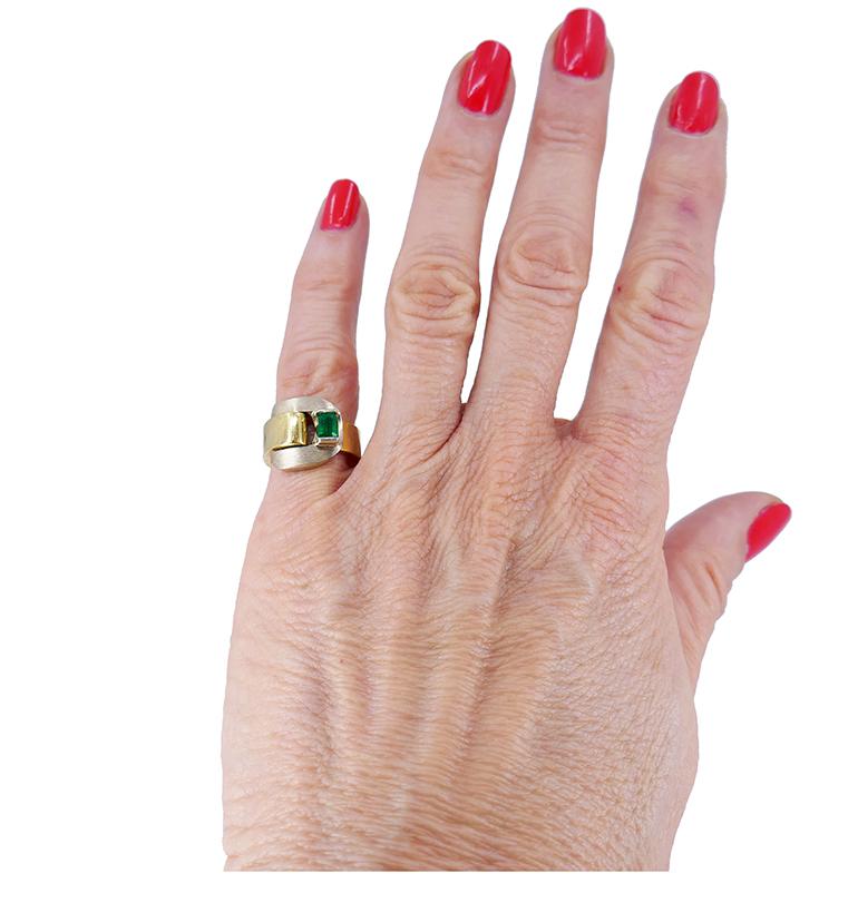 A Gübelin Retro 18k gold ring of a buckle design, featuring an emerald.
The ring beautifully wraps around a finger with a curved white gold buckle. The latter has a matte finish which creates an appealing combo with the polished yellow gold shank.