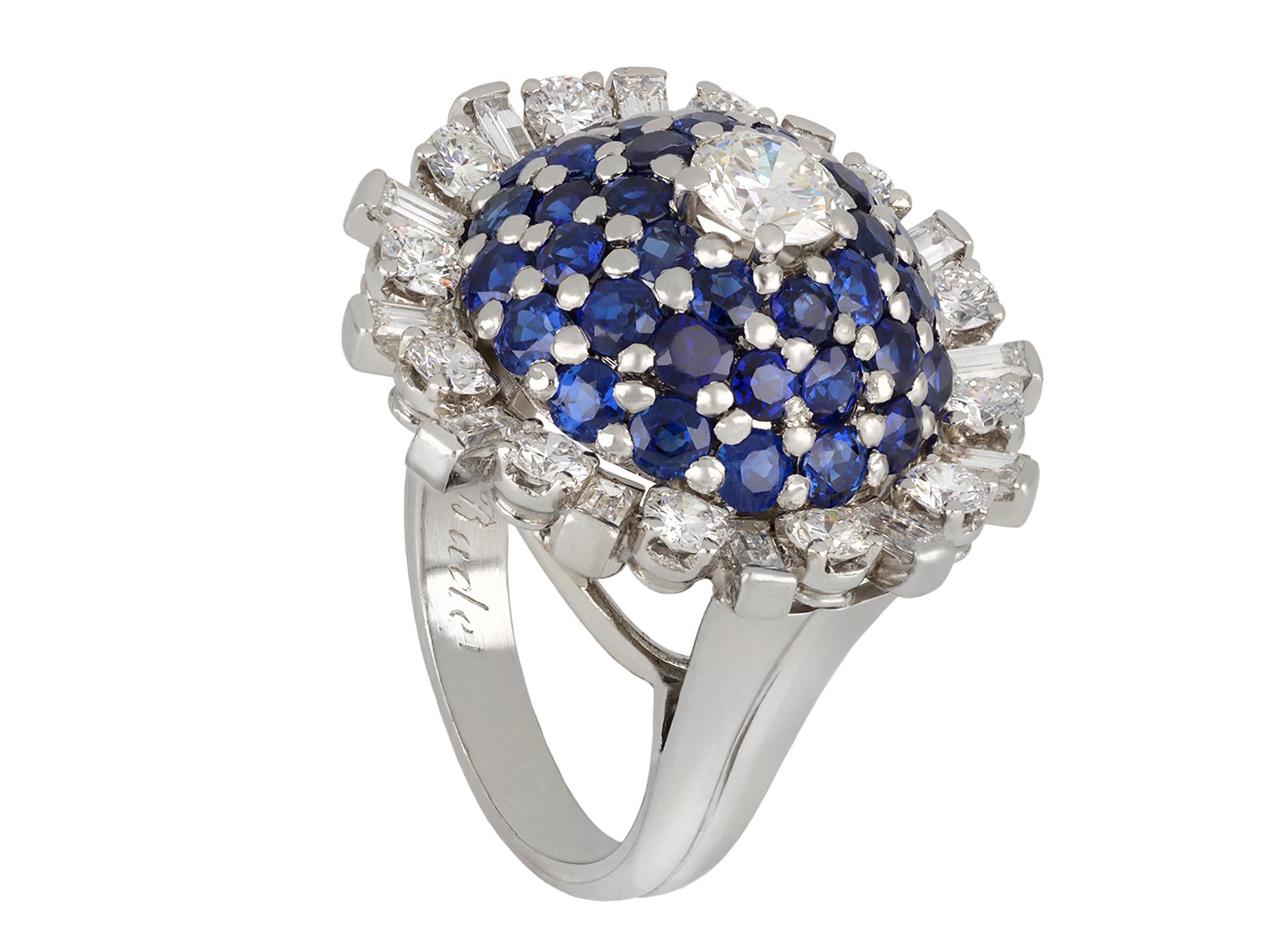 Gubelin sapphire and diamond bombé cocktail ring. Set to centre with one round transitional cut diamond in an open back claw setting with an approximate weight of 0.80 carats, flanked by a cluster of forty round old cut natural unenhanced sapphires