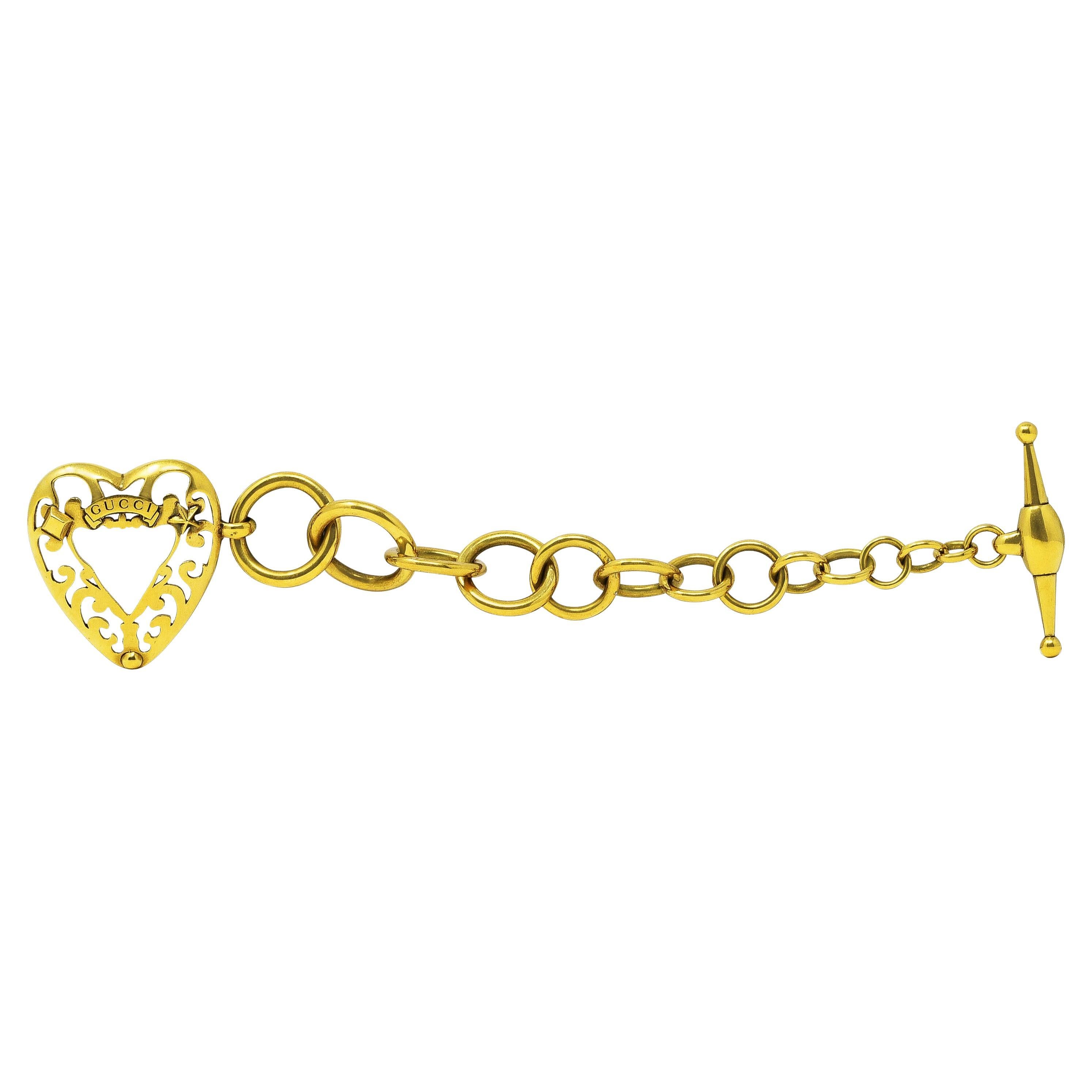 Toggle bracelet is comprised of round circular links that graduate in size. Featuring an oversized open-heart charm. Pierced with scrollwork, emblazoned 'Gucci', and accented by star and stud motifs. Completed by an oversized toggle bar. Italian