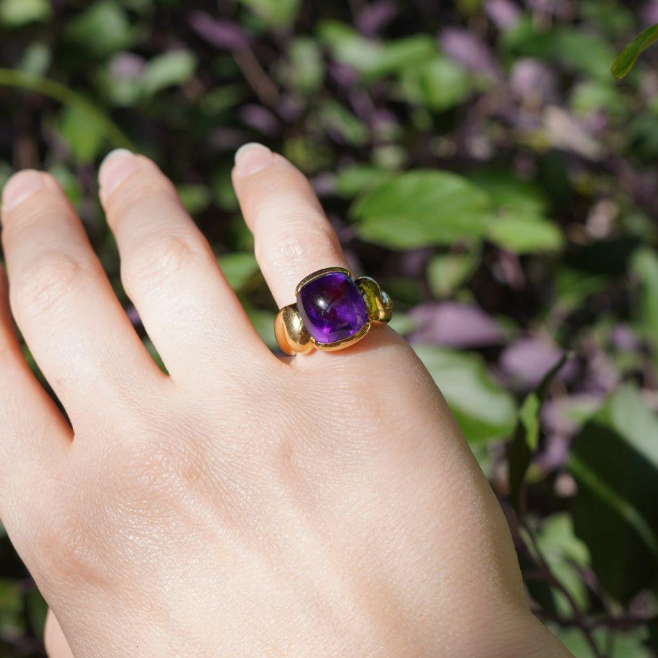 Cette bague Gucci est réalisée en or jaune 18 carats et présente en son centre une audacieuse améthyste taillée en cabochon. La pierre précieuse est sertie d'un chaton et encadrée par des épaules sculpturales aux contours doux qui se fondent