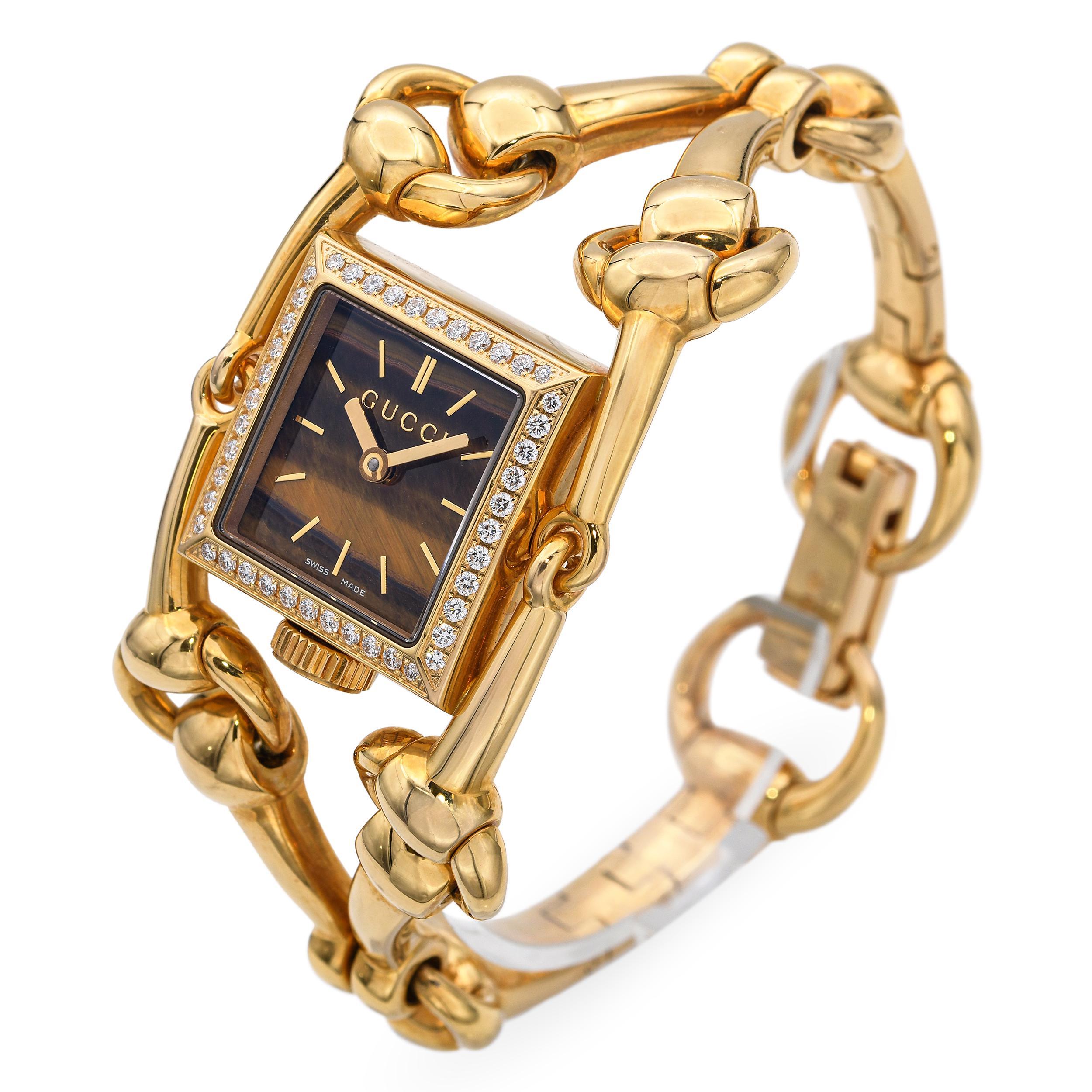 Diese exquisite Gucci Signoria Uhr ist aus massivem 18-karätigem Gelbgold gefertigt und verfügt über das ikonische, vom Pferdchen inspirierte Armbanddesign der Marke. Das Zifferblatt ist aus natürlichem Tigerauge gefertigt und weist warme,