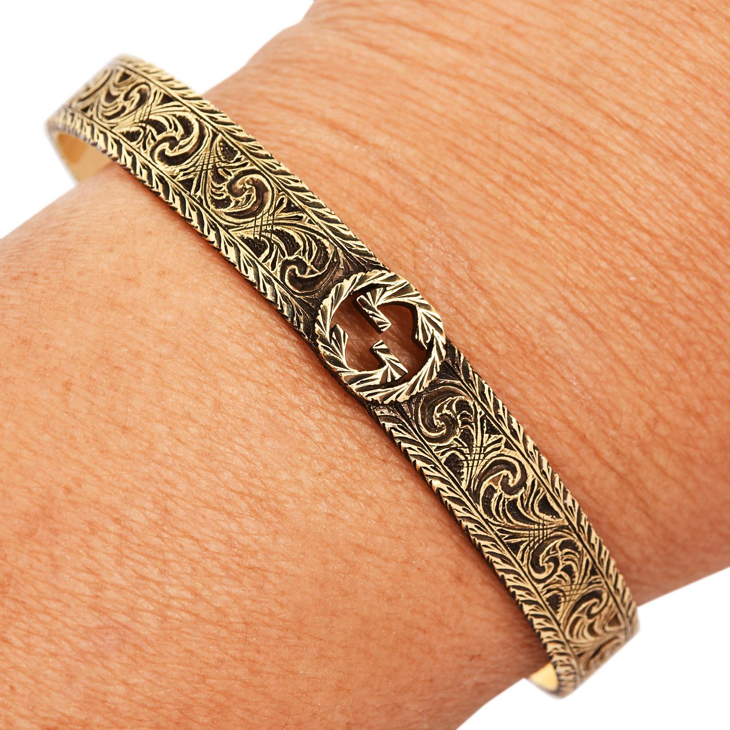 Il bracciale Gucci in oro giallo 18 carati mette in risalto l'inconfondibile motivo GG incorniciato da un dettagliato bordo in stile corda, che unisce l'eleganza classica al lusso moderno. La texture ricca e il design audace rendono questo bracciale