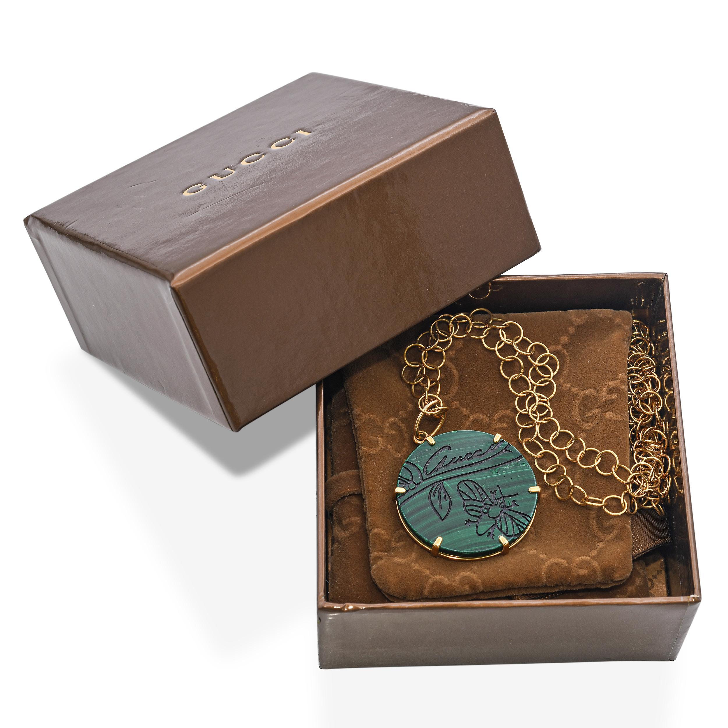 Diese luxuriöse Gucci-Halskette mit Anhänger ist aus 18 Karat Gelbgold gefertigt und zeigt eine leuchtende Malachitscheibe mit dem ikonischen Flora St. Tropez Motiv. Die satten Grüntöne des Malachits werden durch den warmen Schimmer des polierten