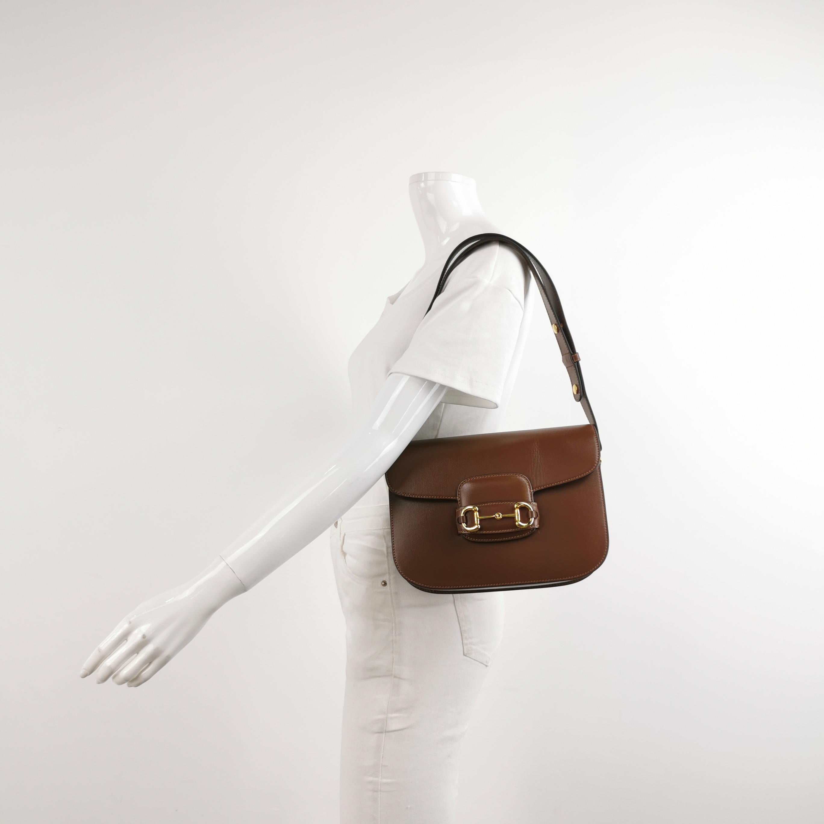 Made from premium calfskin leather in a classic neutral caramel brown color, this Gucci Horsebit 1955 shoulder bag is a must-have for any fashion enthusiast. The renowned gold-tone Gucci Horsebit takes center stage on the front, while the bag is