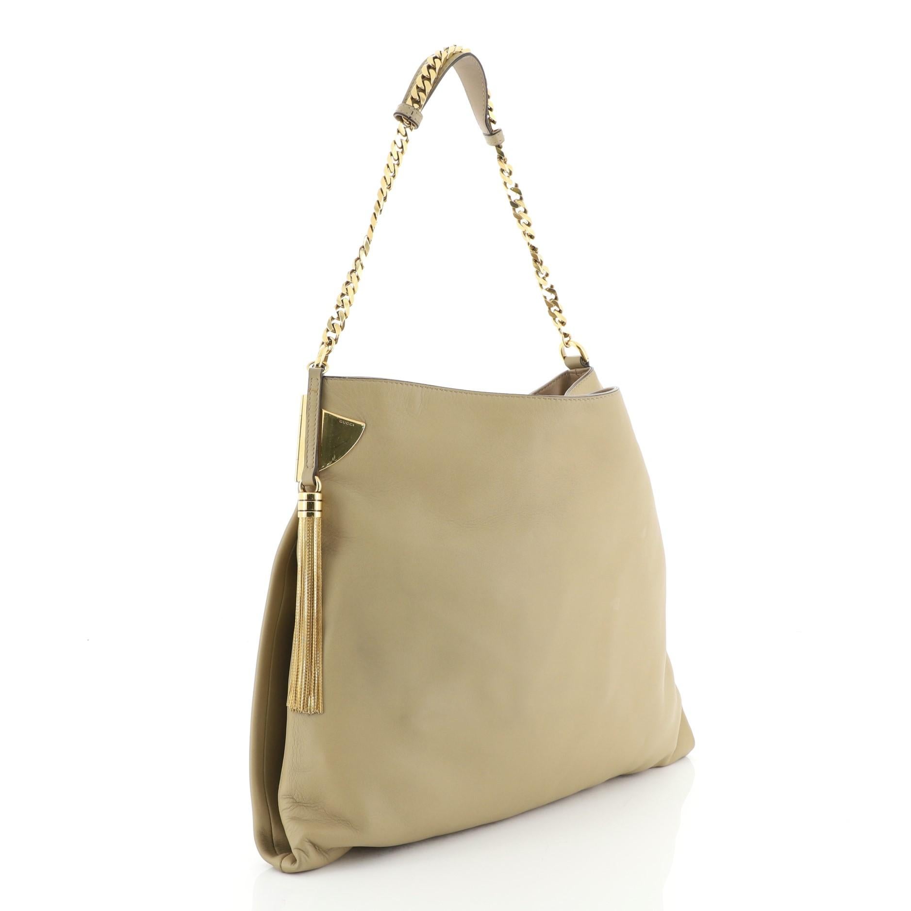 This Gucci 1970 Hobo Leather Medium, crafted from neutral leather, features side cuff and tassel accents, chain link strap with leather pad and gold-tone hardware. Its magnetic snap closure opens to a neutral fabric interior with side zip pocket.