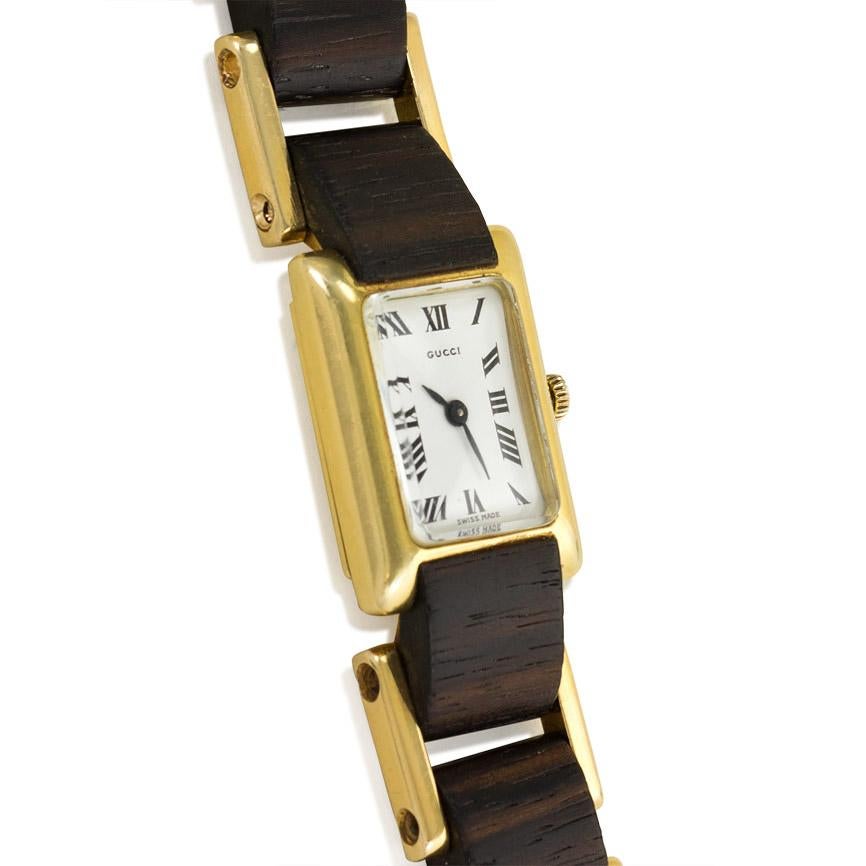 A tank-style watch with macasser ebony and gold links, featuring a rectangular face with Roman numerals, in 18k. Gucci, Italy #846; made by Alexis Barthelay, France, with Swiss movement.

Watch face: 1