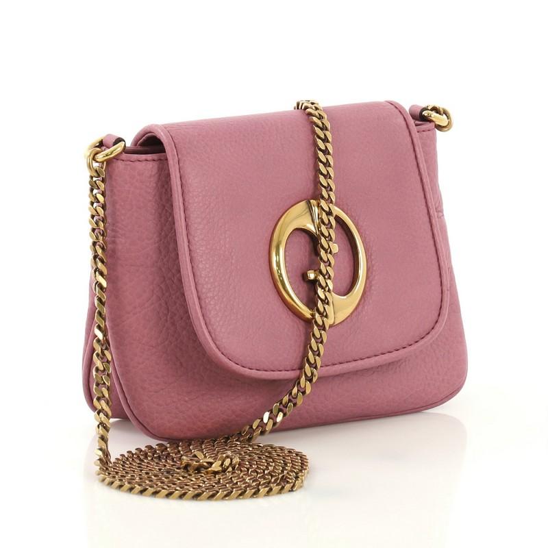 This Gucci 1973 Crossbody Bag Leather Small, crafted from pink leather, features GG detailing on its flap, chain link strap, and aged gold-tone hardware. Its hidden magnetic snap closure opens to a beige suede interior with side slip pocket.