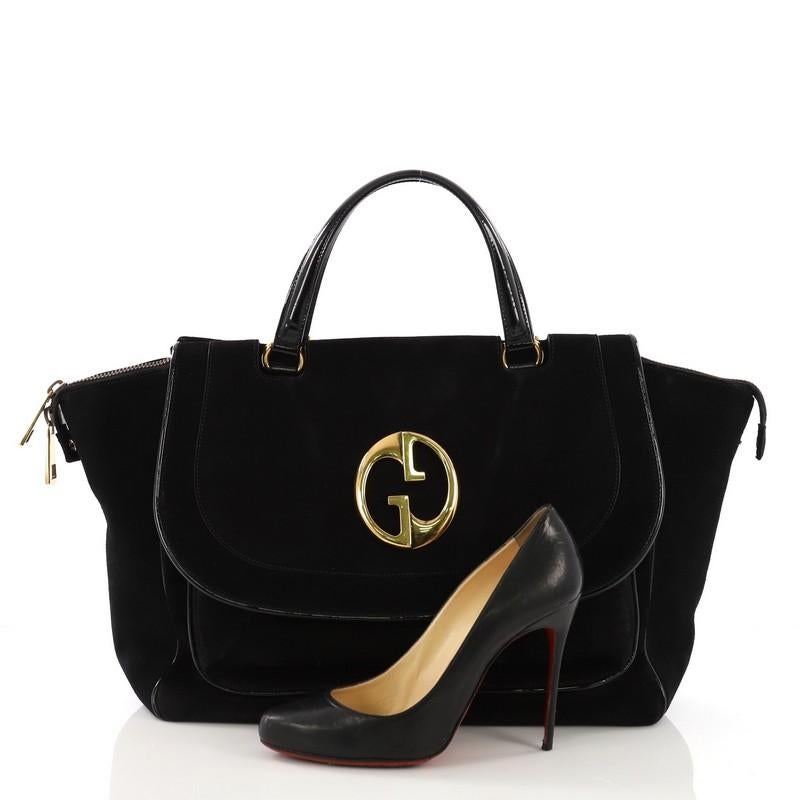 This Gucci 1973 Top Handle Bag Suede Medium, crafted from black suede, features dual flat handles, vintage-style GG logo on the flap, protective base studs and gold-tone hardware. Its two-way zip closure opens to a black fabric interior with zip and