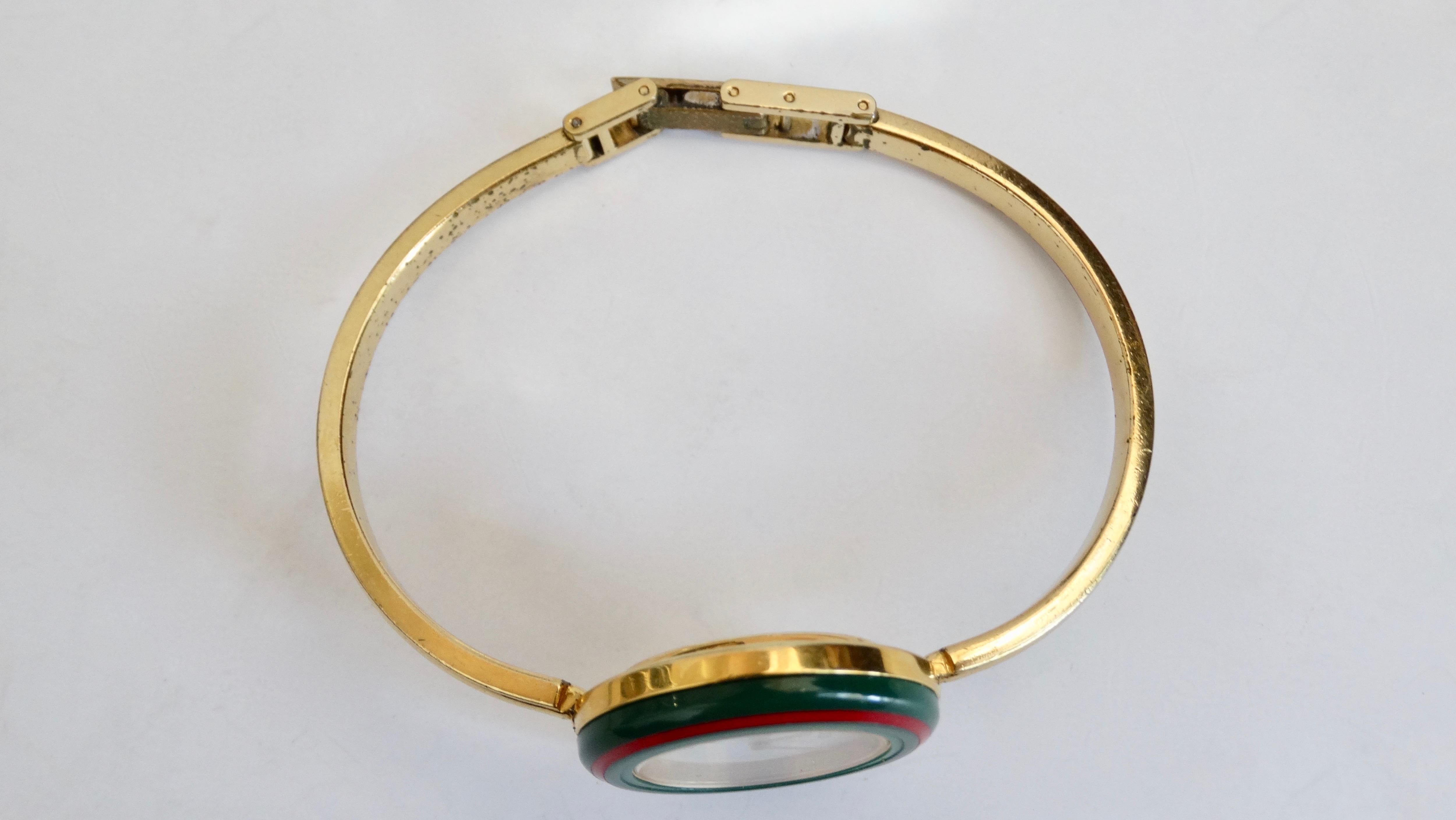 Your new everyday watch is here! Circa 1980s, this Gucci wrist watch features gold hardware, a bangle bracelet and five interchangeable metallic bezels including the classic red and green stripe. A classic timepiece! Includes original box. Wrist