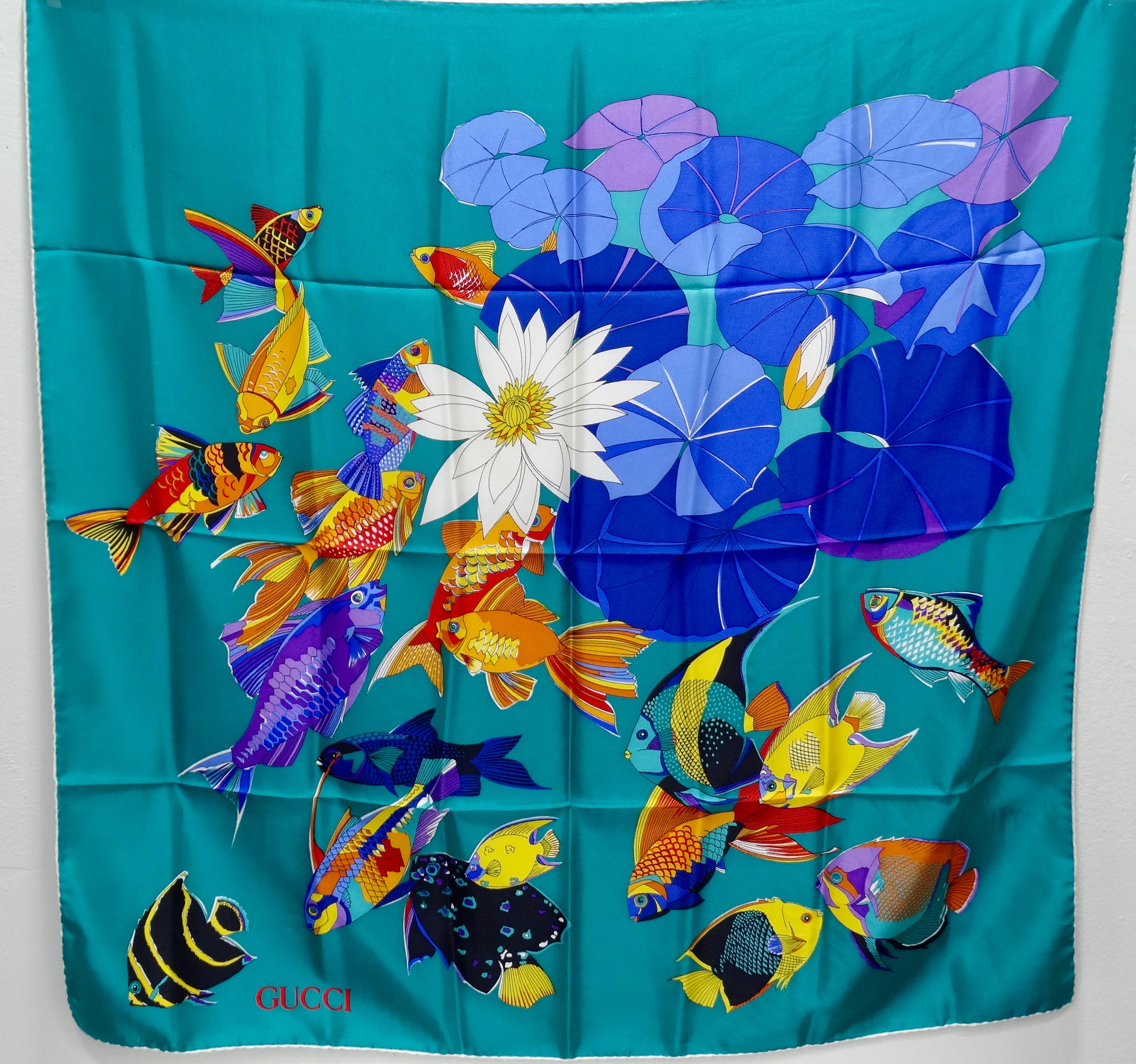 Add this amazing vintage piece to your collection! Circa 1980s, this amazing teal Gucci Silk scarf features a vibrant multi-colored fish motif in the center with contrasting lily pads. At the base is the Gucci signature in red. Rolled edges. Unique