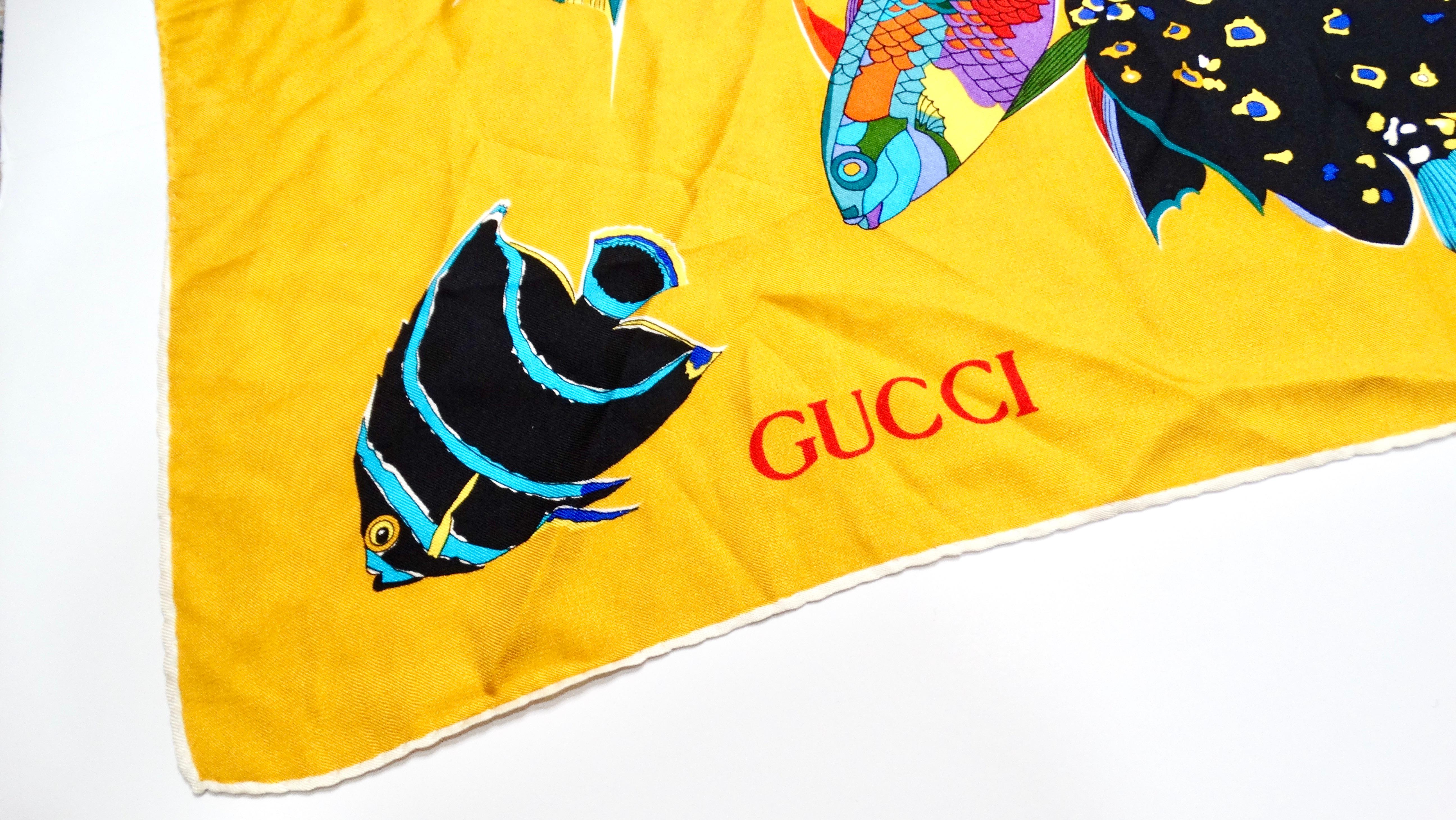 Embrace the vibrant charm of the 1980s with this stunning Gucci Silk Yellow Floral & Fish Motif Printed Scarf. Adorned with a colorful motif that perfectly captures the essence of nature's beauty, this scarf is crafted from luxurious silk, offering