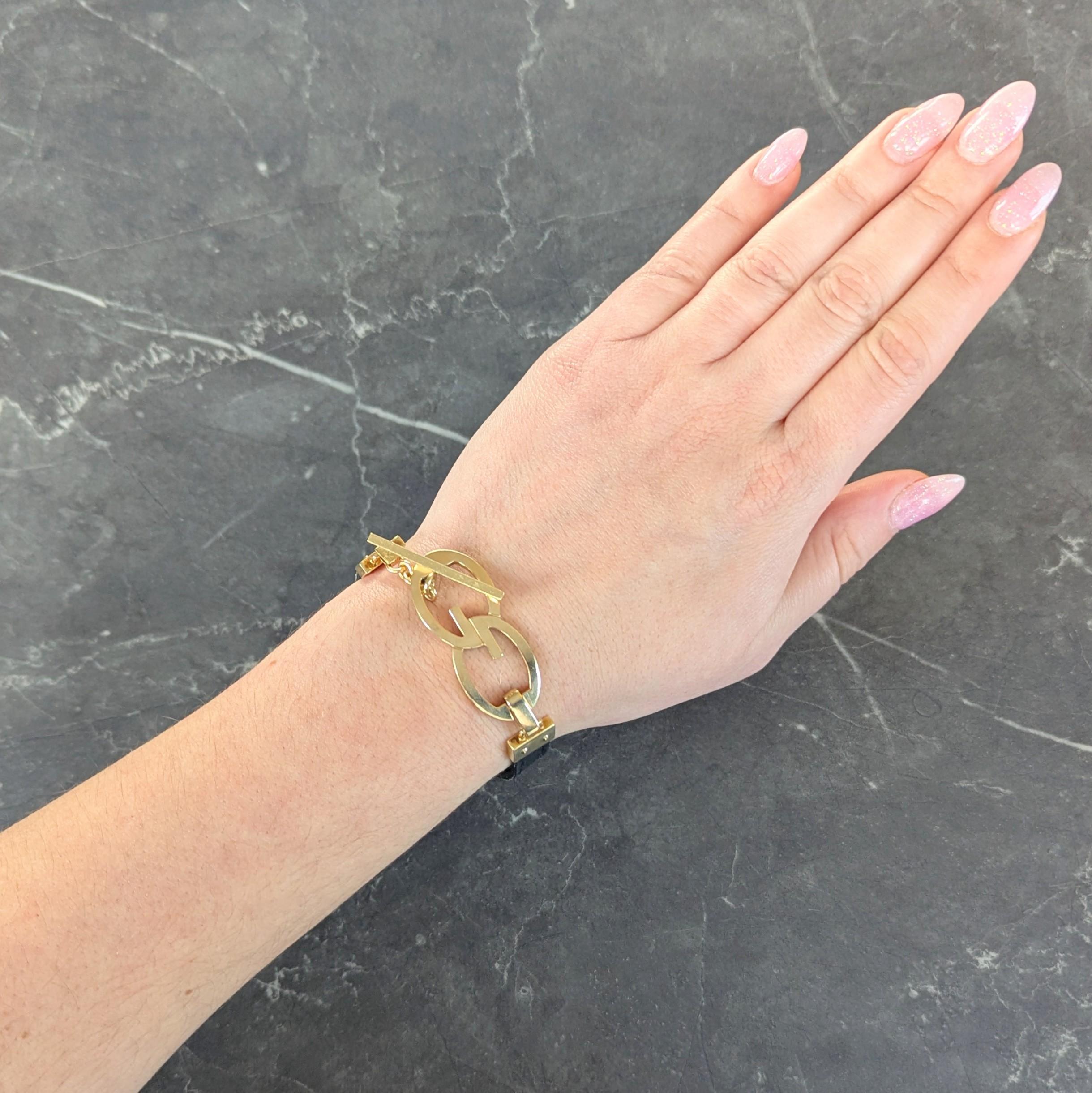 Conçu comme un bracelet en cuir noir avec des terminaisons en or
Fermoir à motif 