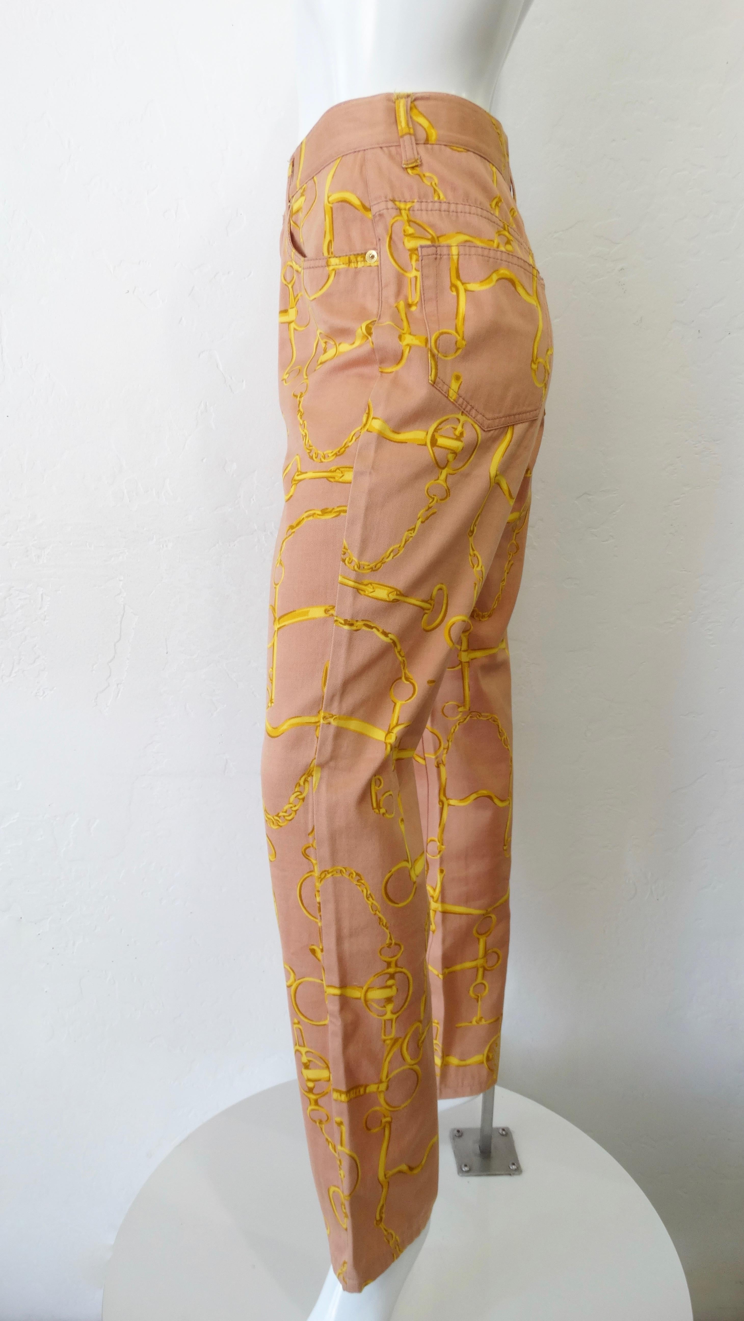 A pair of statement pants are a necessity! Circa 1990s, these Gucci high waisted jeans are a coral color and feature a contrasting gold horse bit pattern. Includes Gucci embossed buttons and leather patch on the back. Pair with a printed shirt or