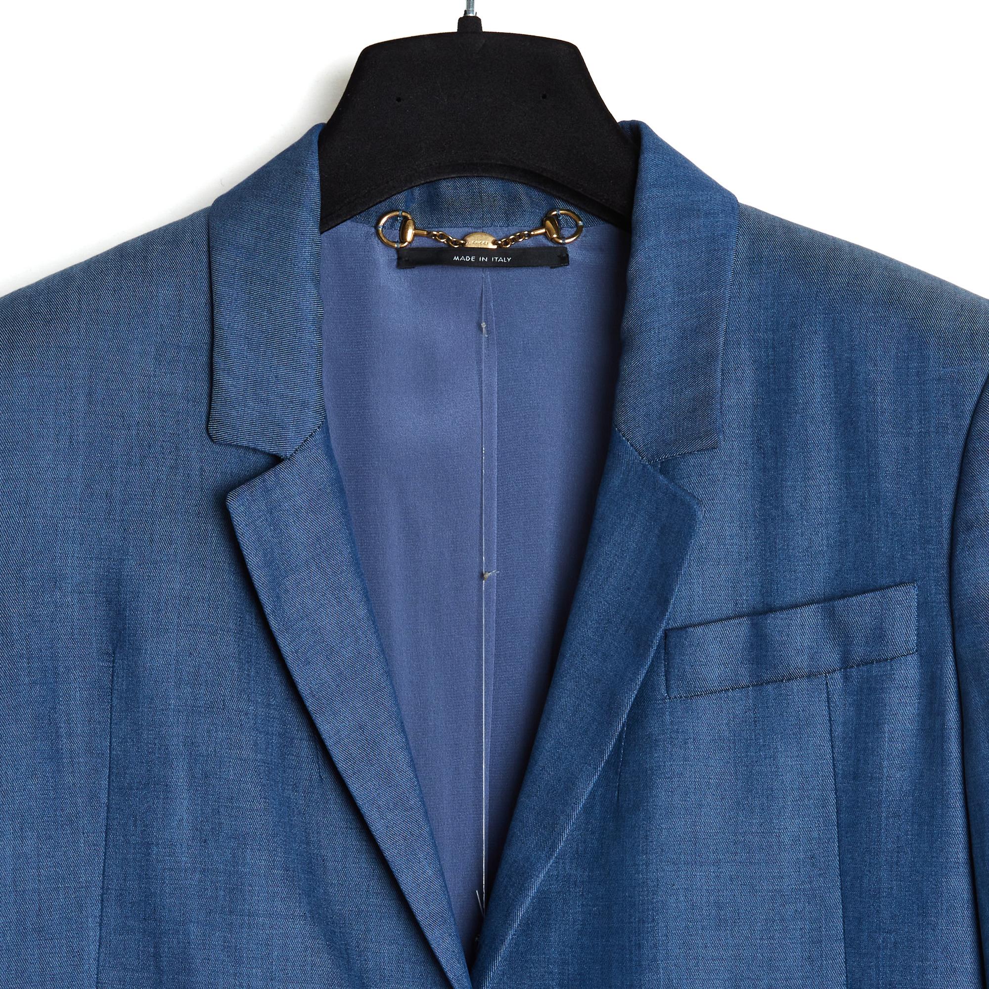 Ensemble de la collection Gucci SS2012 en rayonne bleue (soie artificielle) composé d'une veste droite, long col cranté fermé par un bouton logo Gucci, 1 poche poitrine et 2 poches à rabat sur les hanches (toutes les 3 toujours fermées), manches