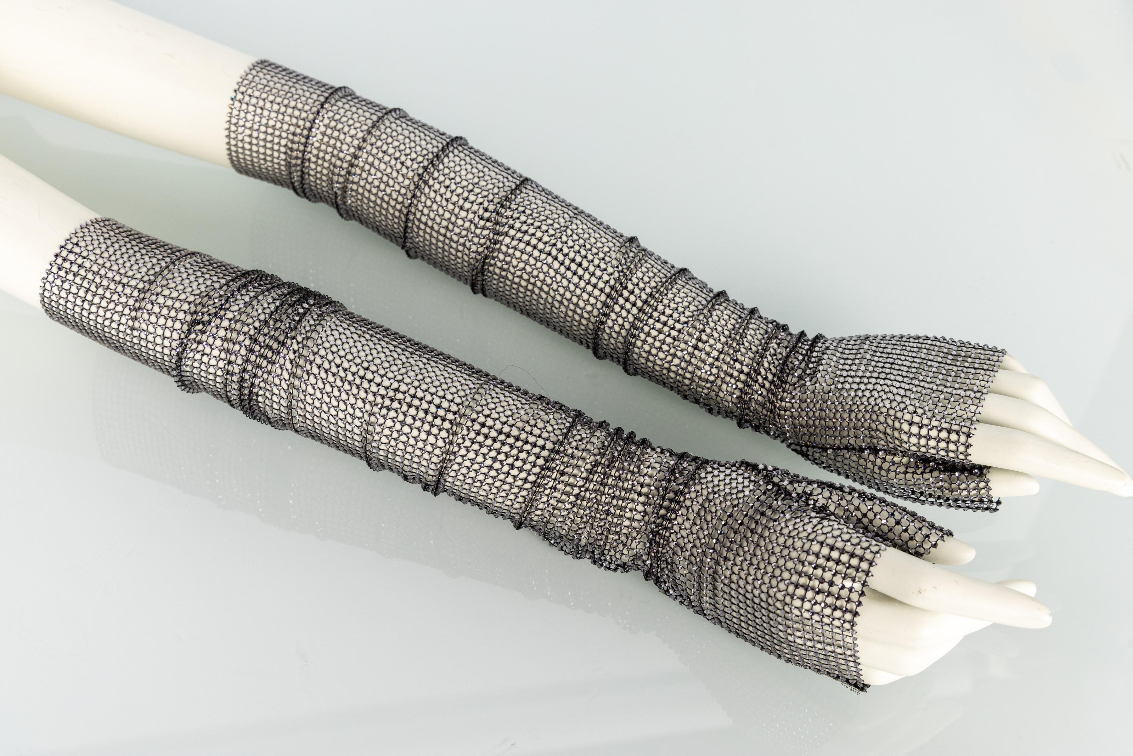 Ces gants sans doigts en maille cristal du défilé 2017 de Gucci constituent une pièce emblématique de l'une des collections phares de la marque. Confectionnées en maille noire souple densément ornée de cristaux scintillants, elles créent un effet de