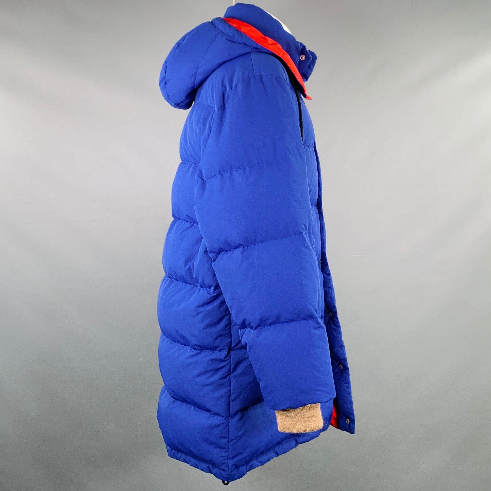 Abrigo GUCCI 2018 by ALESSANDRO MICHELE
en poliamida azul y roja, con un estilo puffer con relleno de plumas de ganso, diseño con capucha y cierre con cremallera y automáticos. Fabricado en Italia.Excelente estado de conservación. 

Marcado:   IT 46