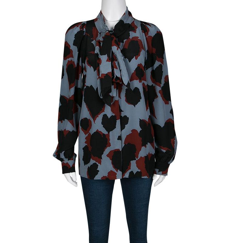 The abstract leaf print adorning this grey-colored blouse is the most striking feature of this Gucci creation. It is cut from 100% silk in a loose structure with stylish tie detail on the neck. Completed with long sleeves, it can be tucked into your