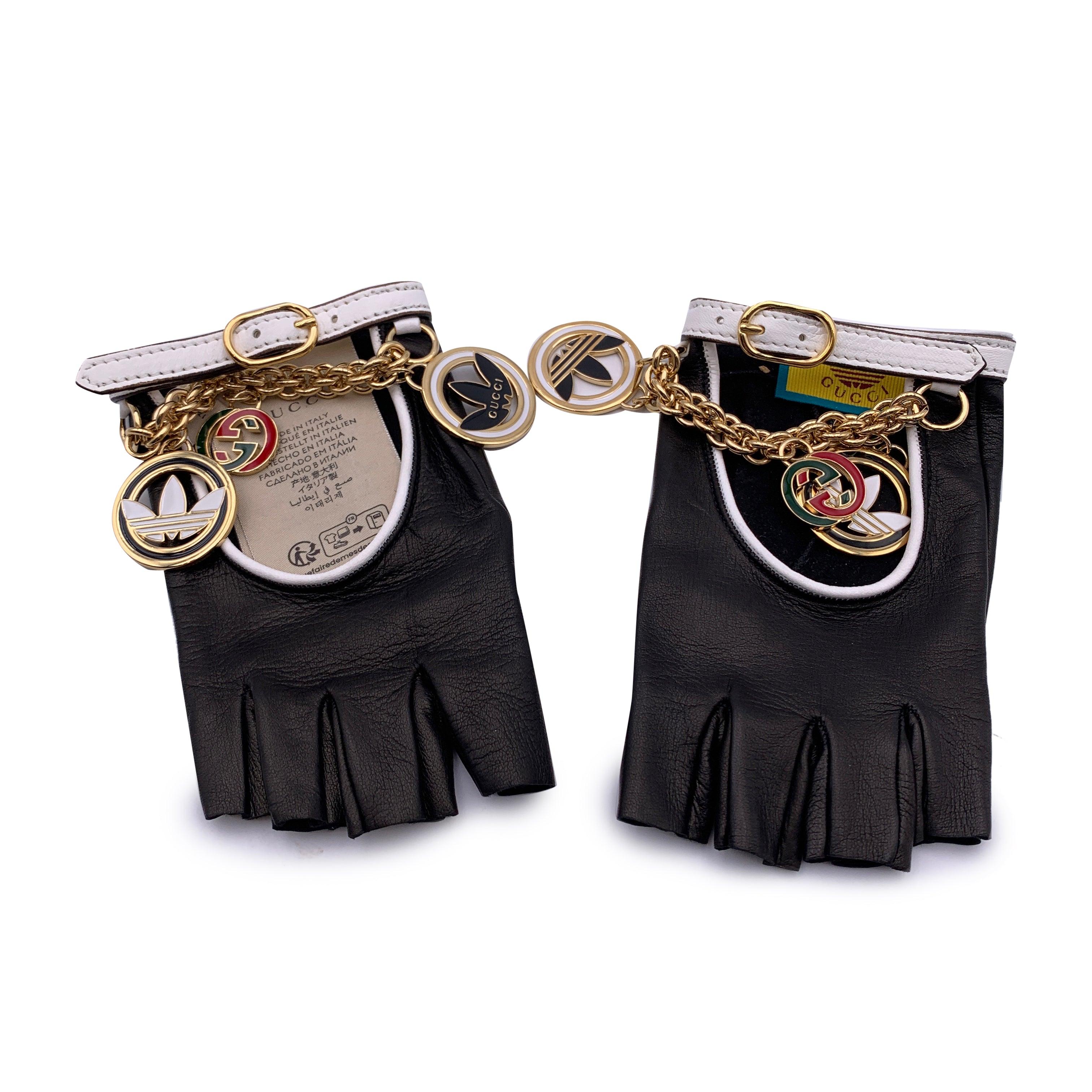 Beautiful black leather driver fingerless gloves from the Gucci x Adidas collection. They feature gold metal chain, enamel Trefoil and Interlocking G details. Black leather with white leather trim. Driver gloves-inspired opening. Adjustable leather