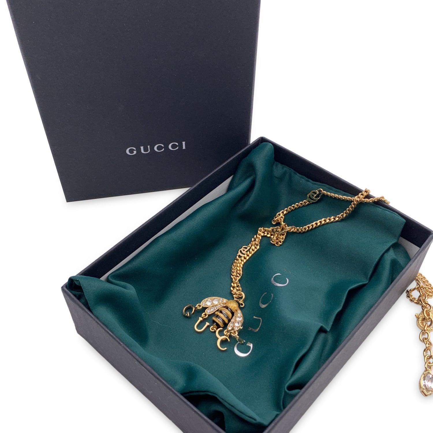 Gucci gold metal chain necklace with bee pendant embellished with crystals and dangling G.U.C.C.I. charms. Lobster clasp closure. Adjustable length. Total length of the chain: 19 inches - 48.3 cm. Condition A+ - MINT Gucci box and pouch included.