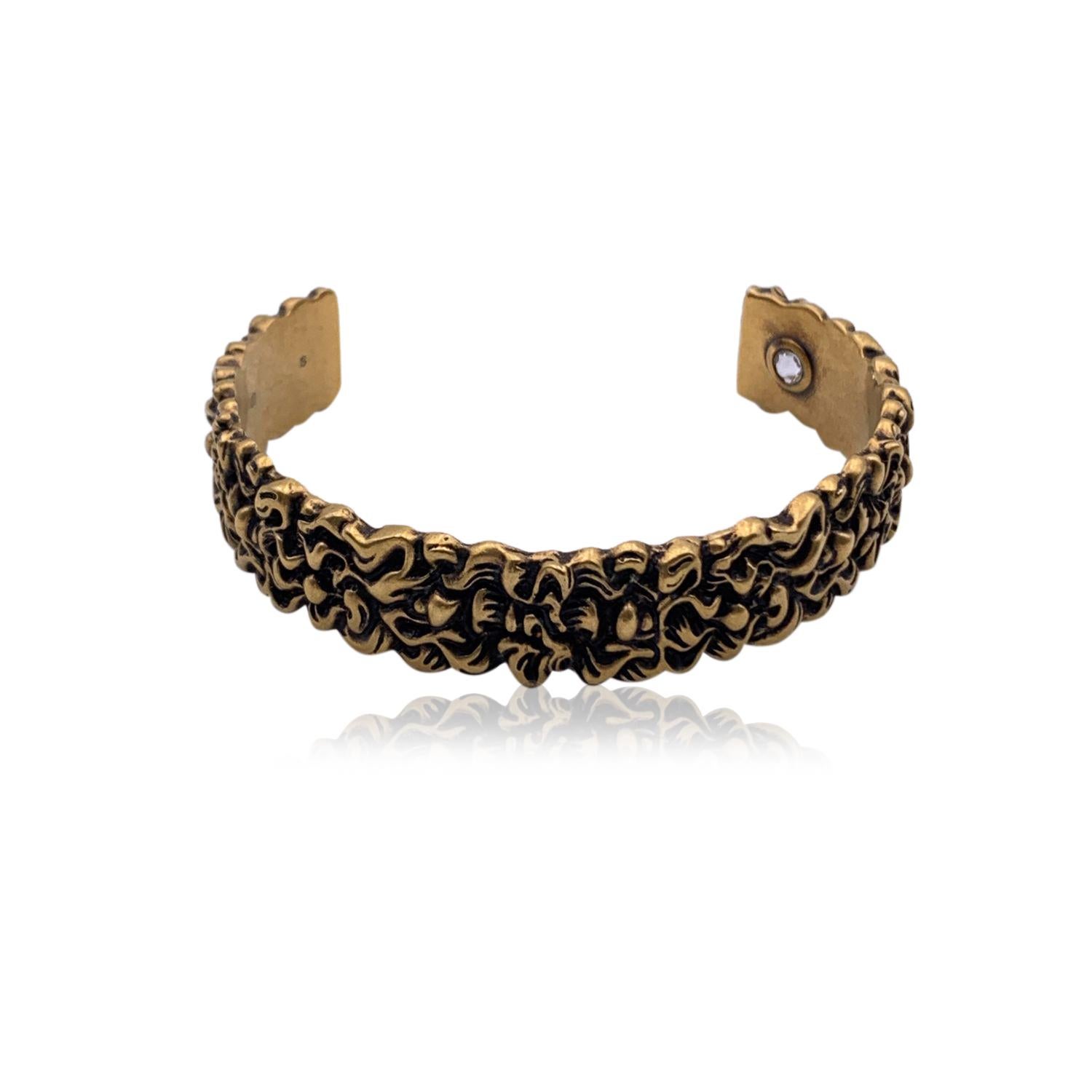 Beautiful cuff bracelet by Gucci. Made in aged gold-tone metal. It features a stunning engraved lion's mane motif . Clear crystal detail set internally. Size: S. Inner circumference: 6.5 inches - 16.5 cm. Inner diameter: 2.25 inches - 5.8 cm. Width: