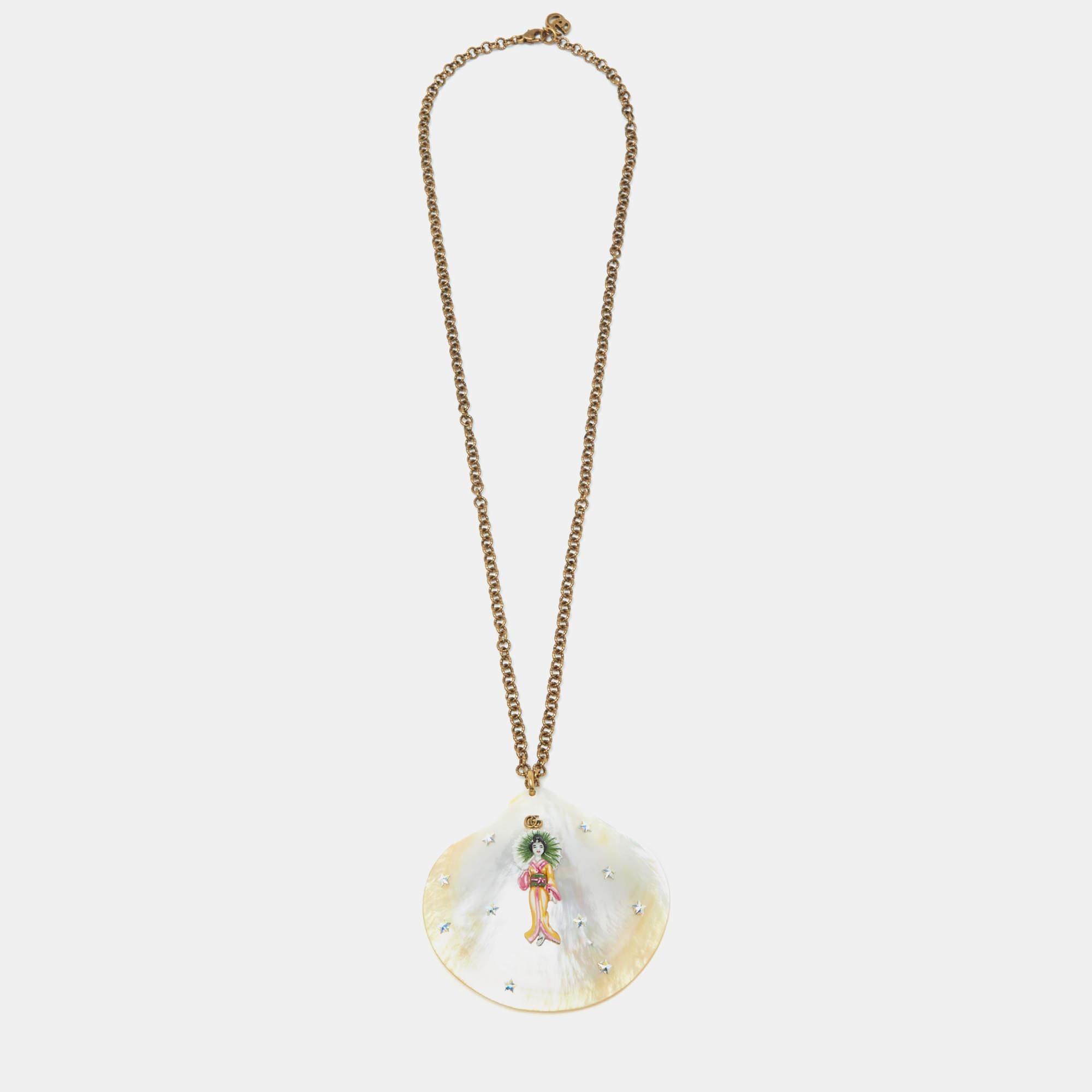 A shell design in mother of pearl, with the detailing of stars, the GG logo, and a Kimon-clad lady is the pendant of this Gucci necklace. A gold-tone chain completes it.

Includes: Original Dustbag, Original Box, Info Booklets

