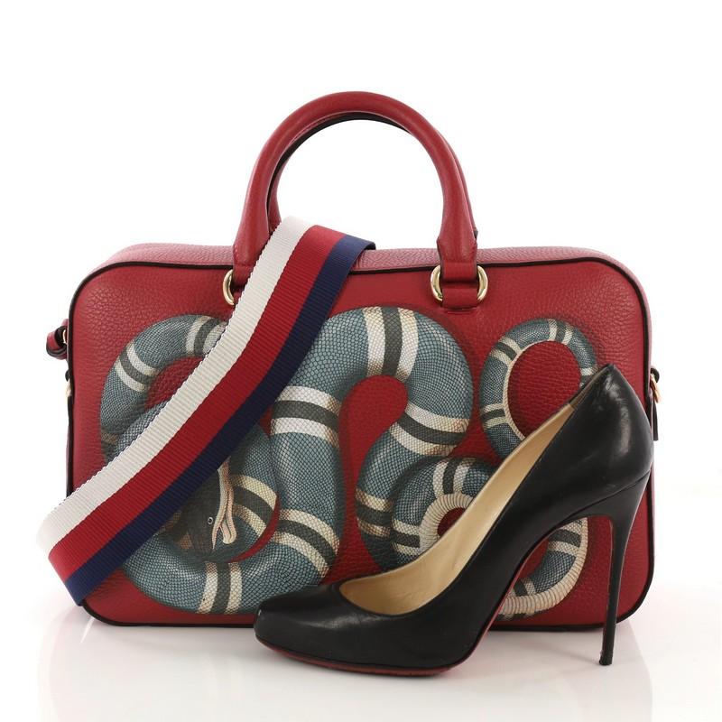 This Gucci Animal Boston Top Handle Bag Printed Leather Medium, crafted from red printed leather, features dual rolled handles, snake print, and gold-tone hardware. Its top zip closure opens to a beige fabric interior with slip and zip pockets.