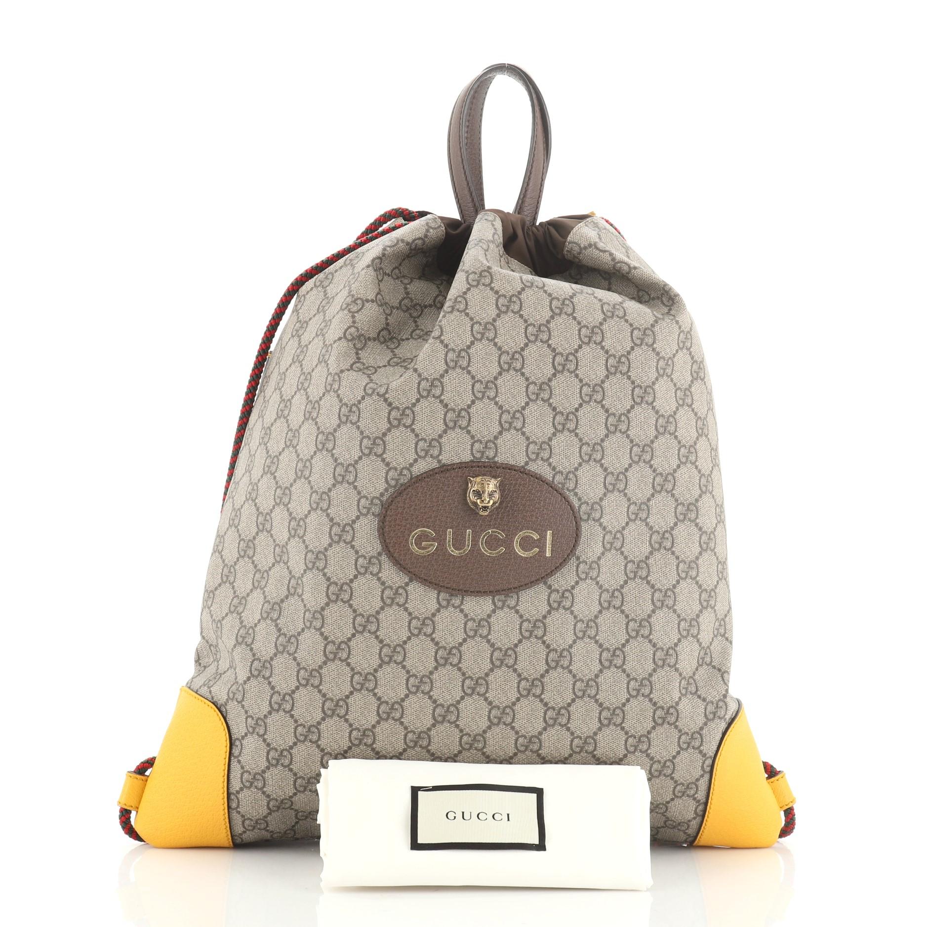 This Gucci Animalier Drawstring Backpack GG Coated Canvas Large, crafted from brown GG coated canvas, features dual top handles, rope straps that double function as drawstring, and aged gold-tone hardware. Its drawstring closure opens to a brown