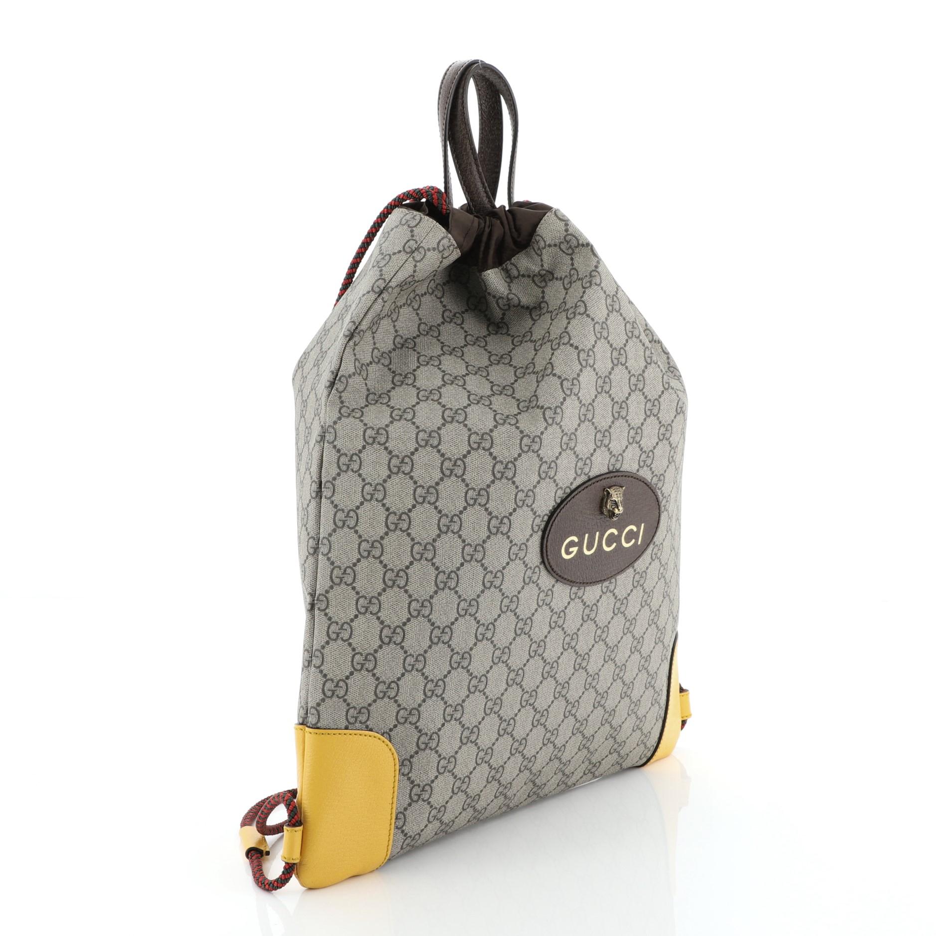 This Gucci Animalier Drawstring Backpack GG Coated Canvas Large, crafted from brown GG coated canvas, features dual top handle, rope straps that double function as drawstring, and aged gold-tone hardware. Its drawstring closure opens to a brown