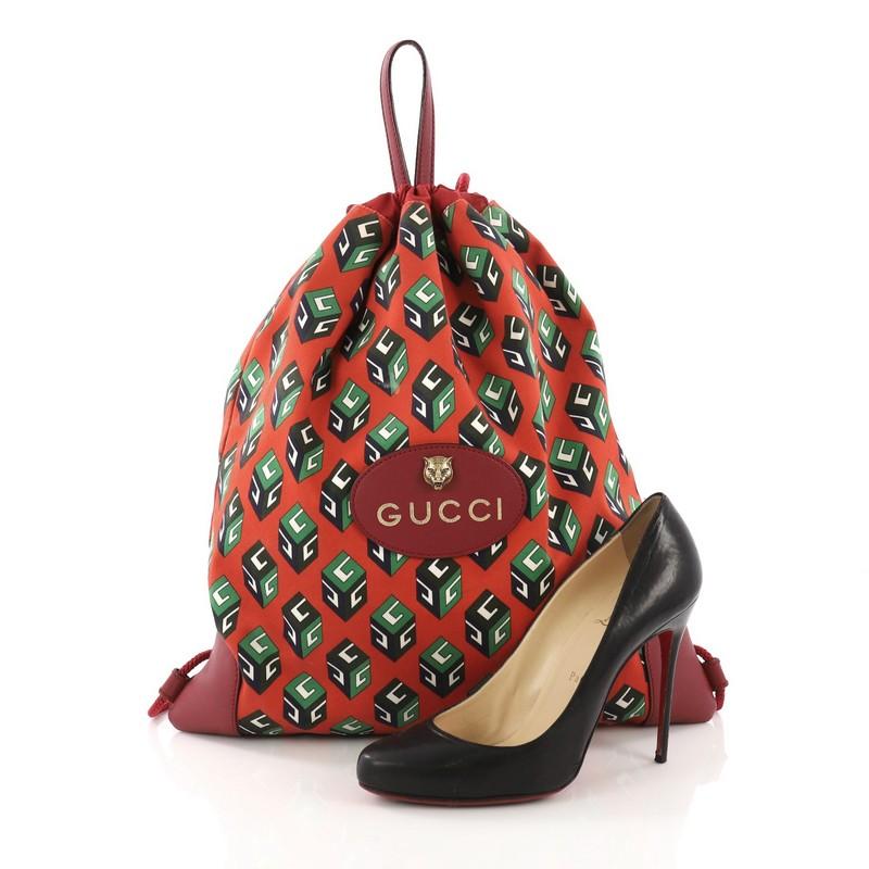 This Gucci Animalier Drawstring Backpack Printed Canvas Large, crafted in red printed canvas, features leather flat top handles, rope shoulder straps, feline head design, and gold-tone hardware. Its drawstring closure opens to a red fabric interior