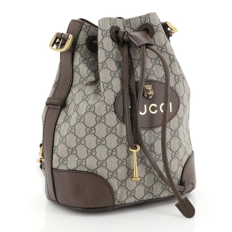 This Gucci Animalier Drawstring Bucket Backpack GG Coated Canvas Mini, crafted from brown GG coated canvas and leather, features adjustable web straps, leather top handle, and aged gold-tone hardware. Its drawstring closure opens to a neutral fabric