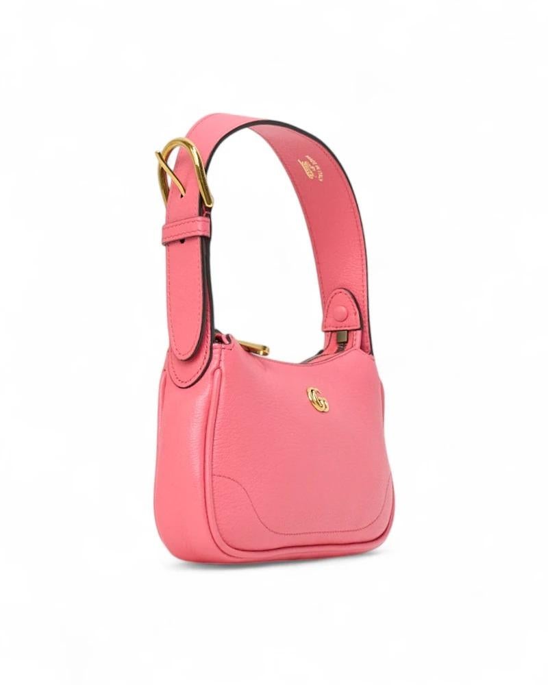 Sac Aphrodite, signature de Gucci, en format mini, réalisé en cuir grainé rose et orné de ferrures dorées. Doté d'une fermeture à glissière et d'une doublure intérieure en daim beige, ce sac est suffisamment spacieux pour contenir l'essentiel.