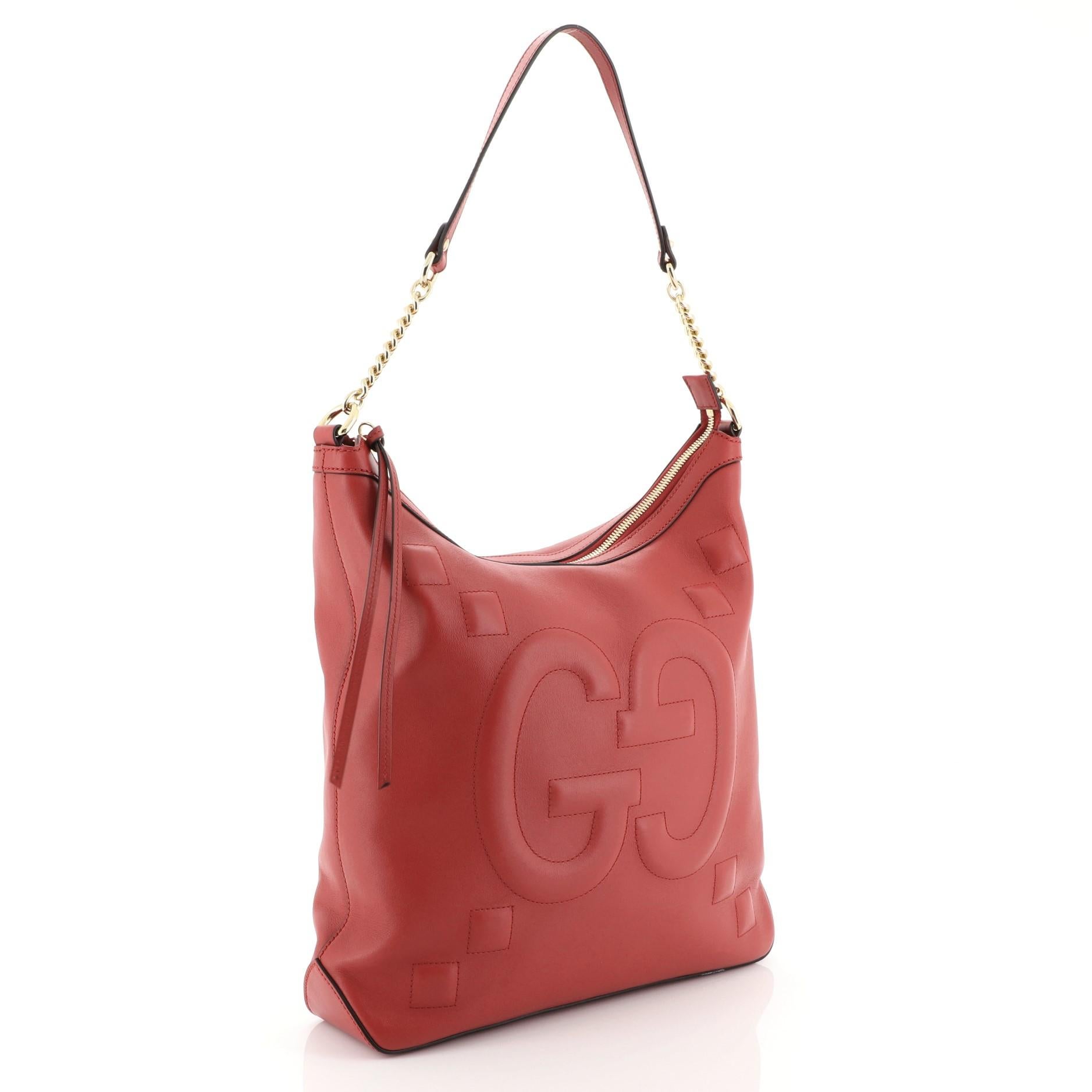 This Gucci Apollo Shoulder Bag GucciGhost Embossed Leather Large, crafted in red embossed leather, features chain link strap with leather pad and gold-tone hardware. Its zip closure opens to a neutral microfiber interior with zip and slip pockets.