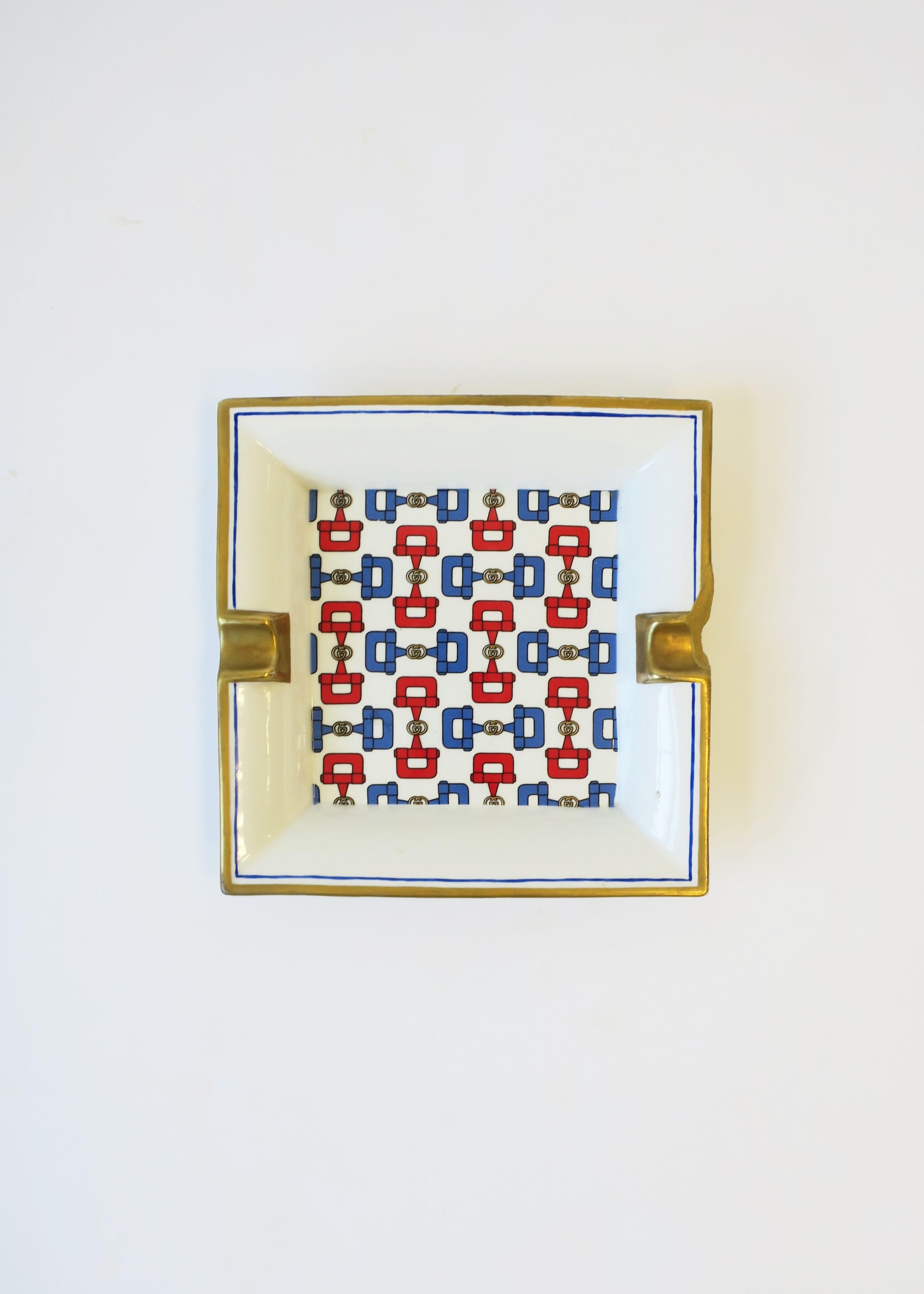 A vintage porcelain Gucci ashtray or vide-poche catchall, circa late-20th century, Italy. This ashtray vide-poche catchall from luxury design house Gucci is white porcelain with iconic double 'GG' and blue and red horse bit design, finished with a