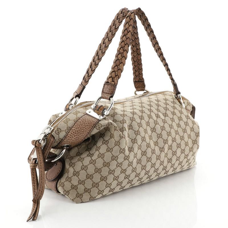 This Gucci Bamboo Bar Shoulder Bag GG Canvas Medium, crafted from brown GG canvas, features braided dual strap handles with bamboo details and silver-tone hardware accents. Its wide-open top showcases a brown fabric interior side zip and slip
