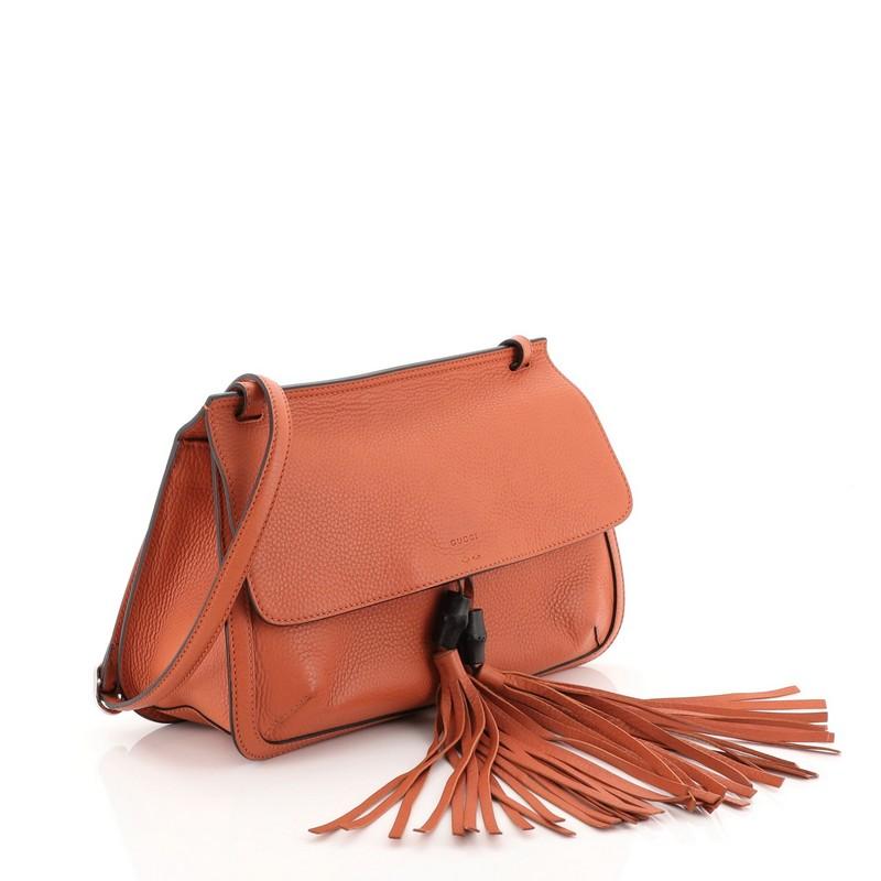This Gucci Bamboo Daily Flap Bag Leather, crafted in orange leather, features frontal flap with bamboo tassel fringe, adjustable leather strap, and silver-tone hardware. Its flap opens to a multicolor fabric interior with side zip and slip pockets.