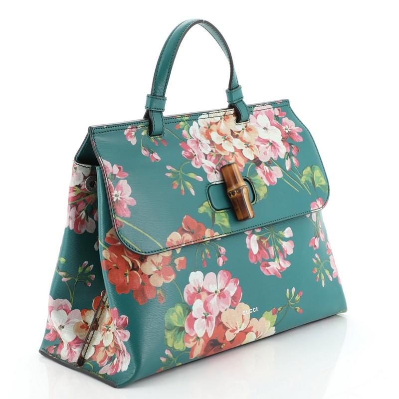 This Gucci Bamboo Daily Top Handle Bag Blooms Print Leather Medium, crafted from green, pink and multicolored leather, features feminine blooms prints, a single looped leather handle, front flap with bamboo twist-lock closure, and aged silver-tone