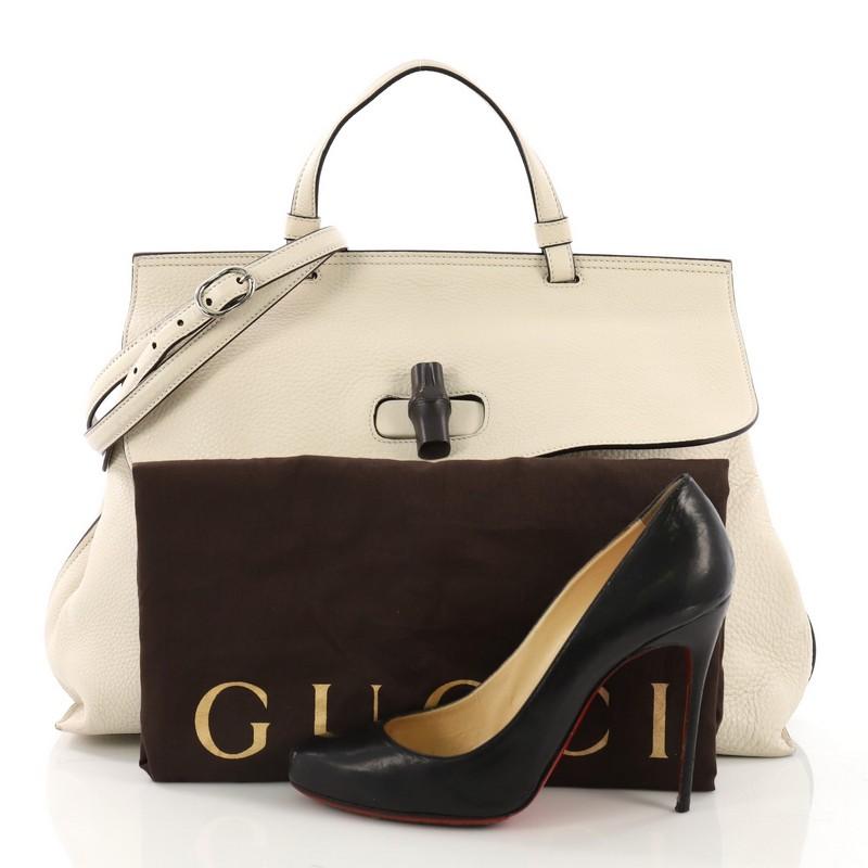 This Gucci Bamboo Daily Top Handle Bag Leather Large, crafted from cream leather, features a flat top handle, frontal flap with turn-lock closure with dark lacquered bamboo detail, and silver-tone hardware. It opens to a beige and green multicolor